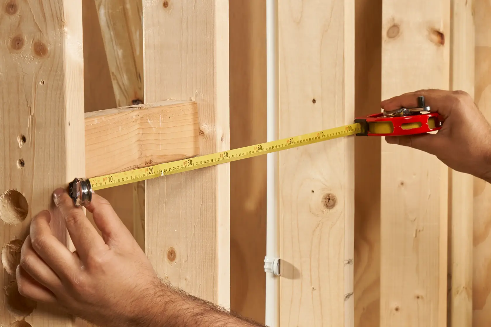 STANLEY 0-34-406 tape measure in use measuring wooden studs, close-up angle.