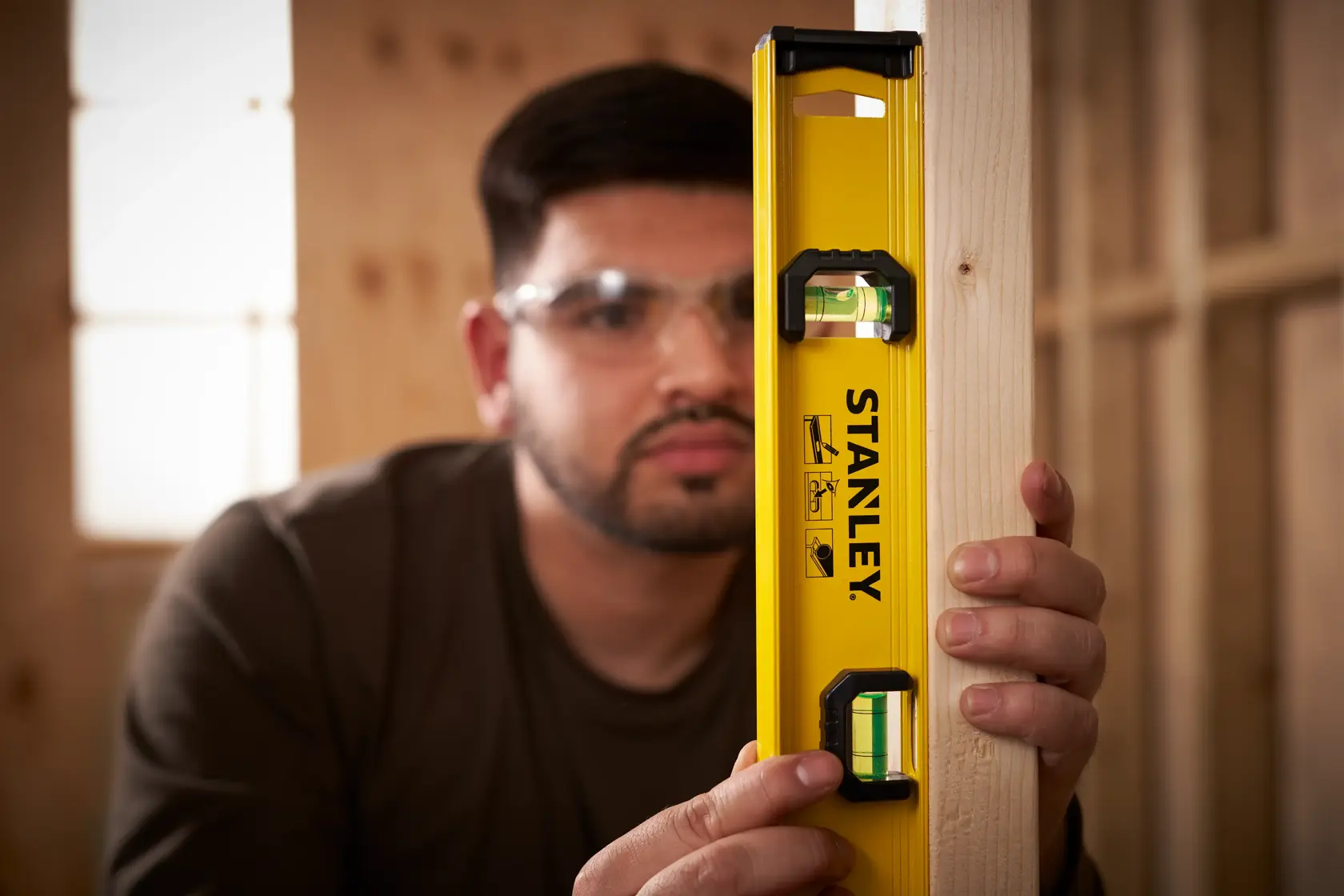 Photo of STANLEY 0-42-073 spirit level being used vertically against a wooden beam in a workshop.