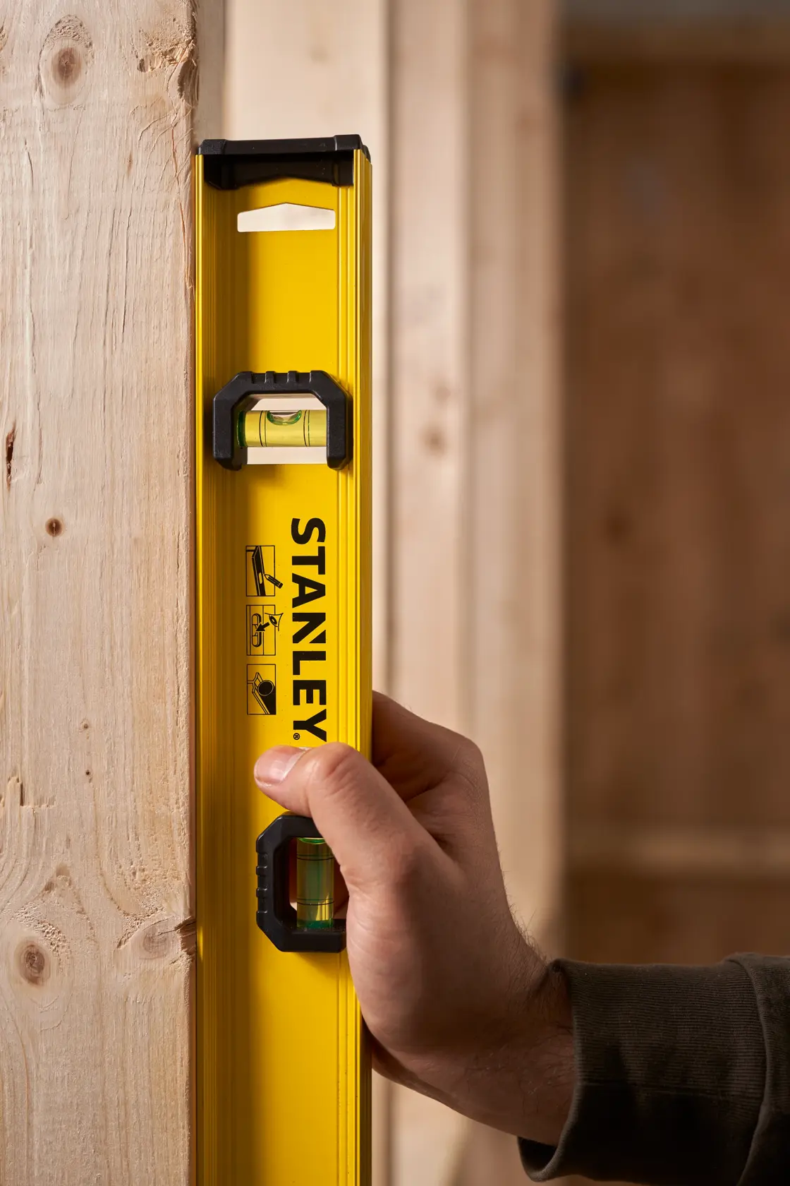 STANLEY 0-42-073 spirit level held vertically against wooden beam, close-up photography.