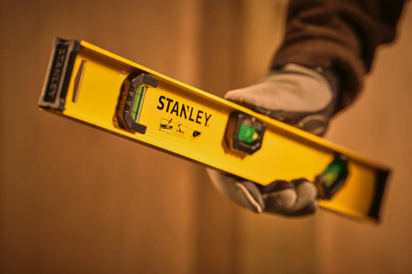 STANLEY 0-42-073 spirit level held in gloved hand, yellow body with visible bubble vial.