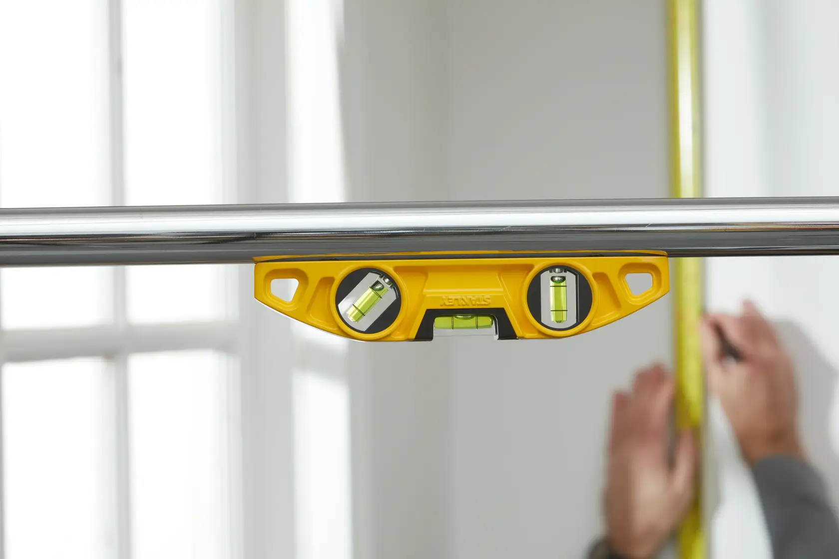 STANLEY 0-43-603 yellow spirit level attached to metal pipe, measuring surface in indoor setting.