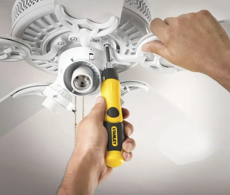 STANLEY 0-63-022 screwdriver used to repair a white ceiling fan, product held in hand, close-up.