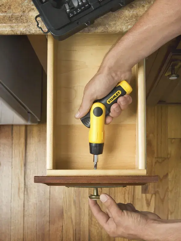 STANLEY 0-63-022 screwdriver being used to install a drawer handle, photography from above on wooden floor.