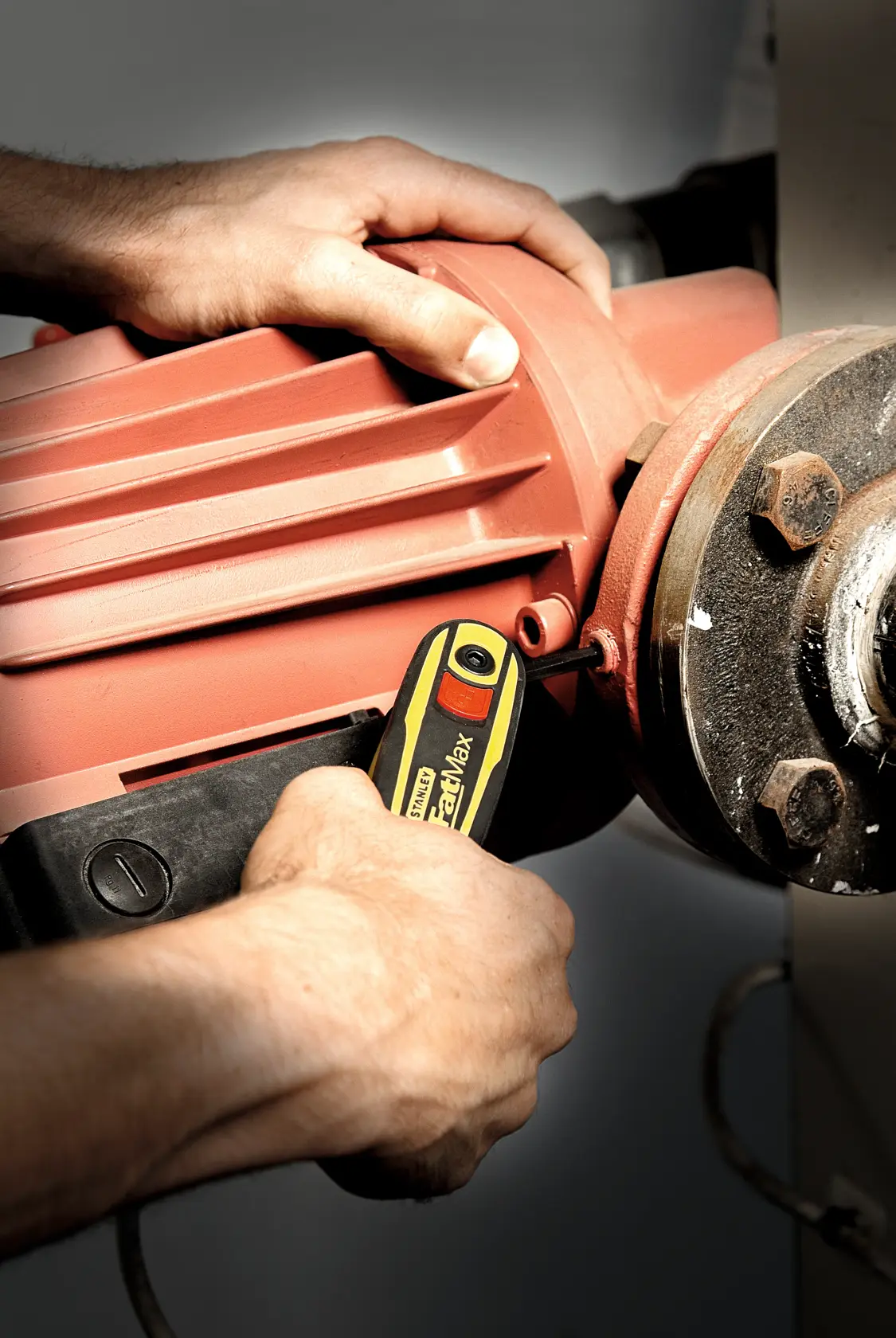 Photo of STANLEY 0-97-553 insulated screwdriver in use tightening a screw on industrial machinery.