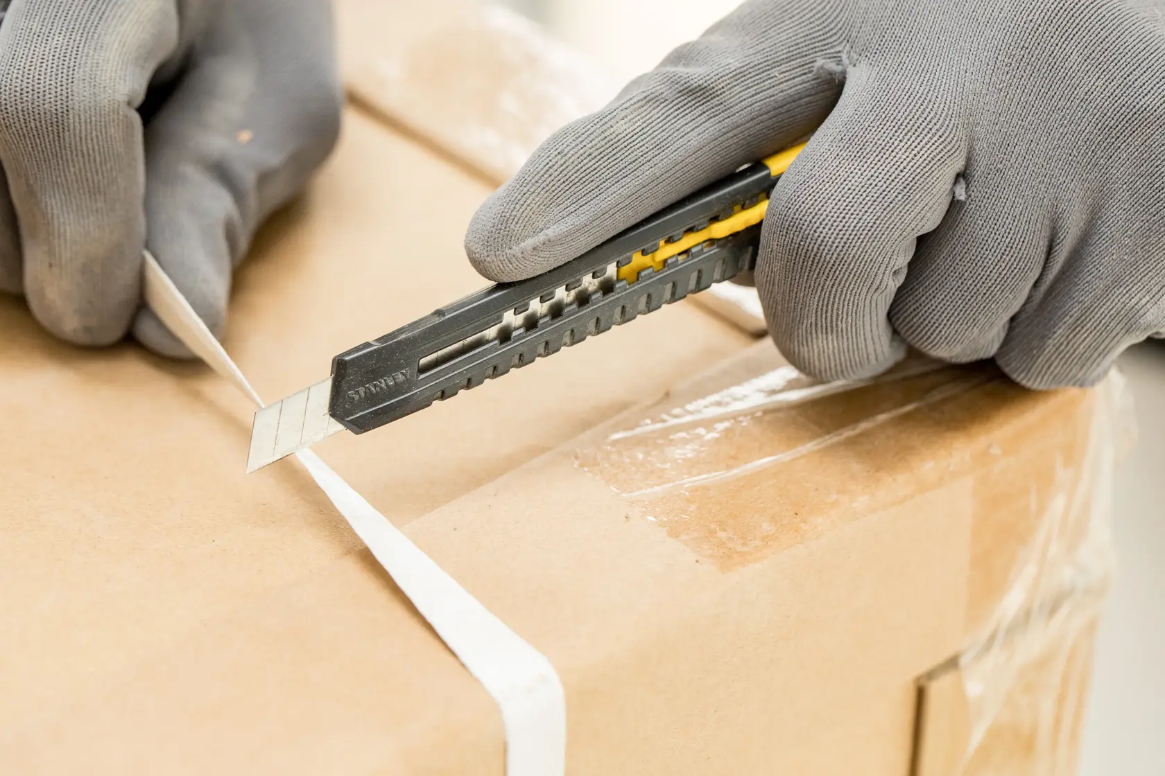 STANLEY 1-10-150 utility knife cutting packing strap on a cardboard box, close-up photography.