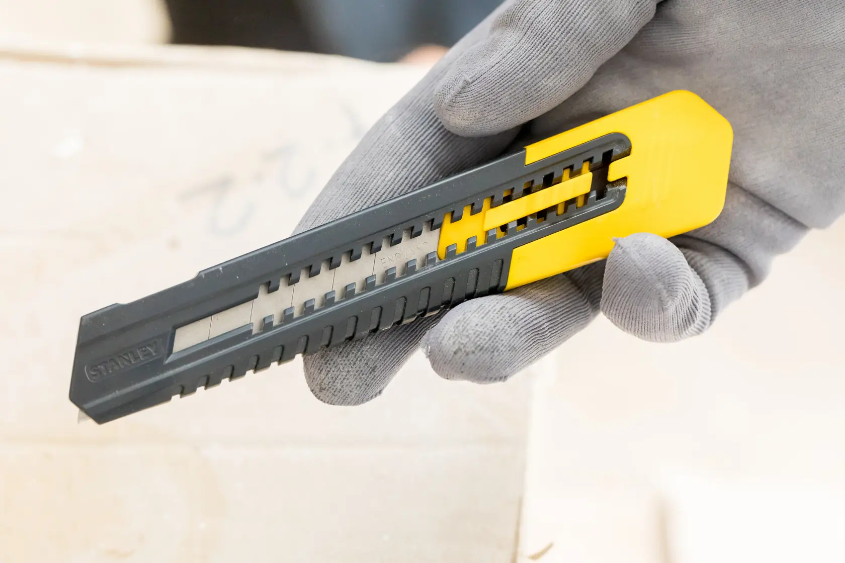 STANLEY 1-10-151 snap-off utility knife, black and yellow, held in gloved hand, close-up photography.