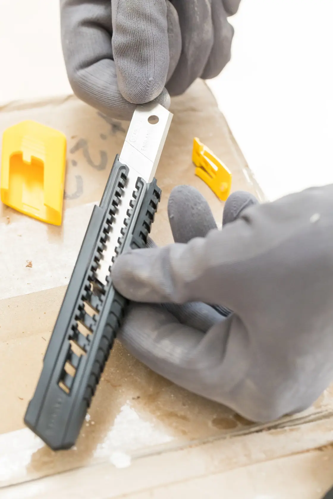 Photo of STANLEY 1-10-151 snap-off utility knife with black handle, gloves holding tool, yellow covers nearby.