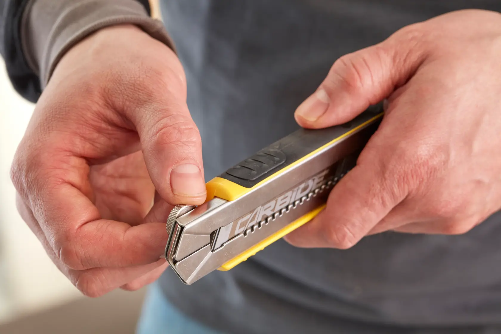 Photo of hands holding a STANLEY 1-10-481 utility knife with carbide blade, close-up view.