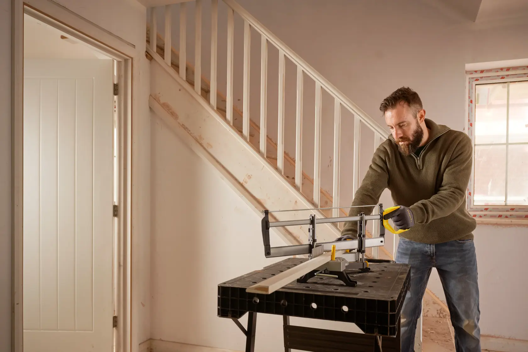 STANLEY 1-20-800 hand saw used on a workbench indoors by a person cutting wood near stairs.