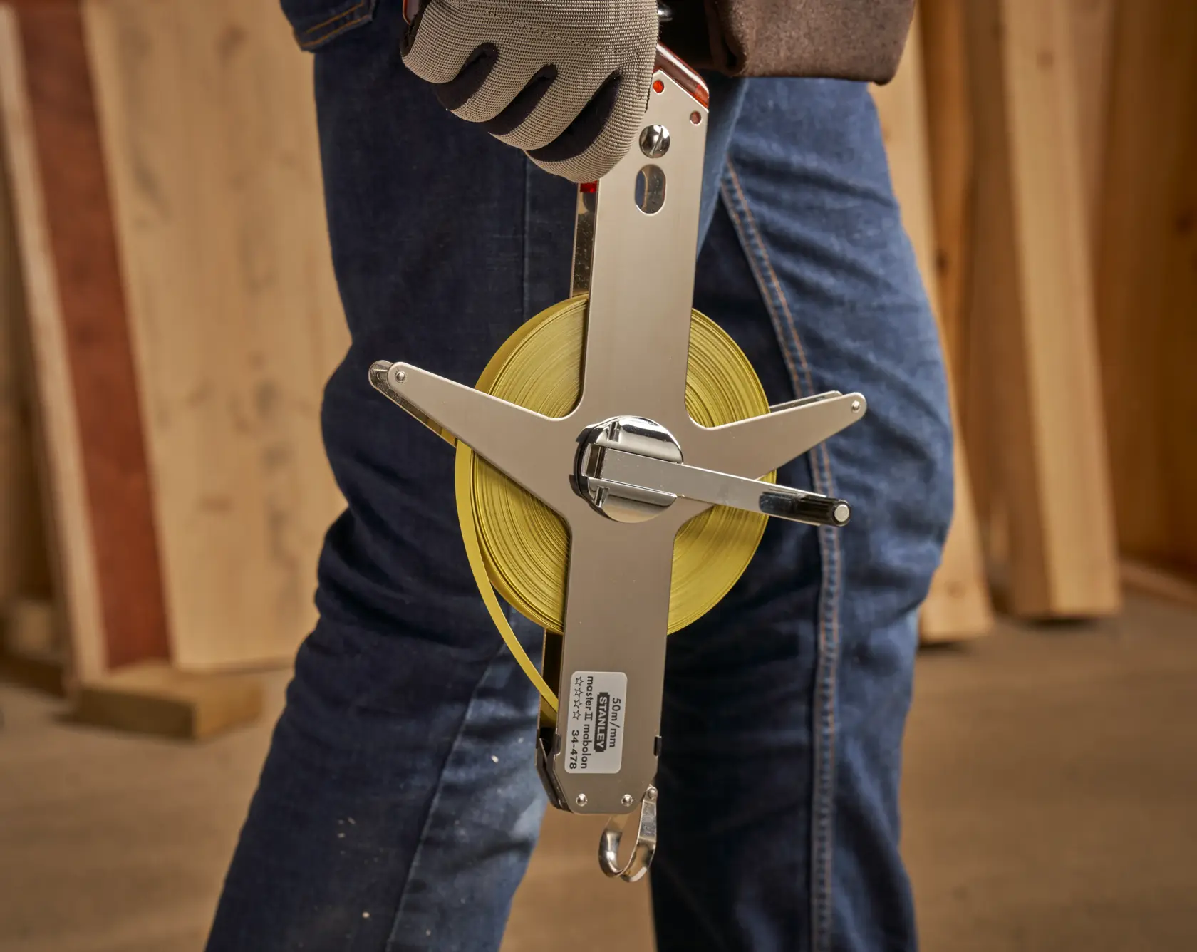 STANLEY 1-34-478 open-frame measuring tape held in hand, yellow blade, construction setting.