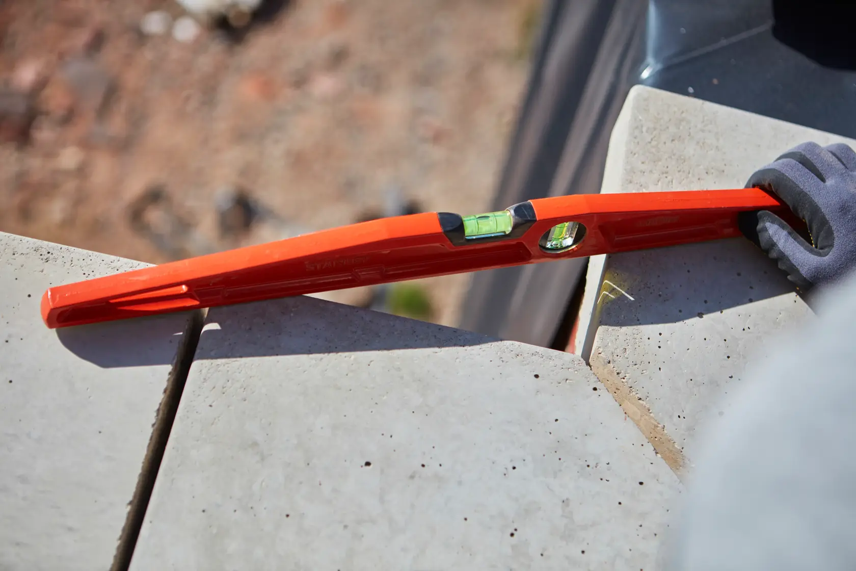 STANLEY 1-42-314 red spirit level in use on concrete tiles, close-up outdoor scene, product photography.