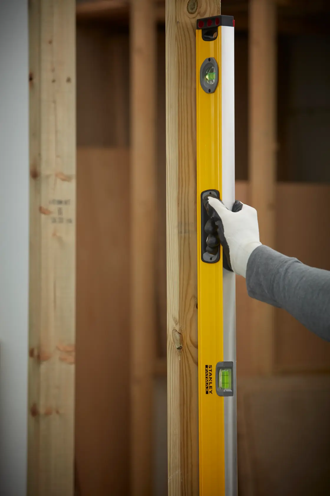 STANLEY 1-43-548 level tool held vertically against wooden frame, user wearing glove.