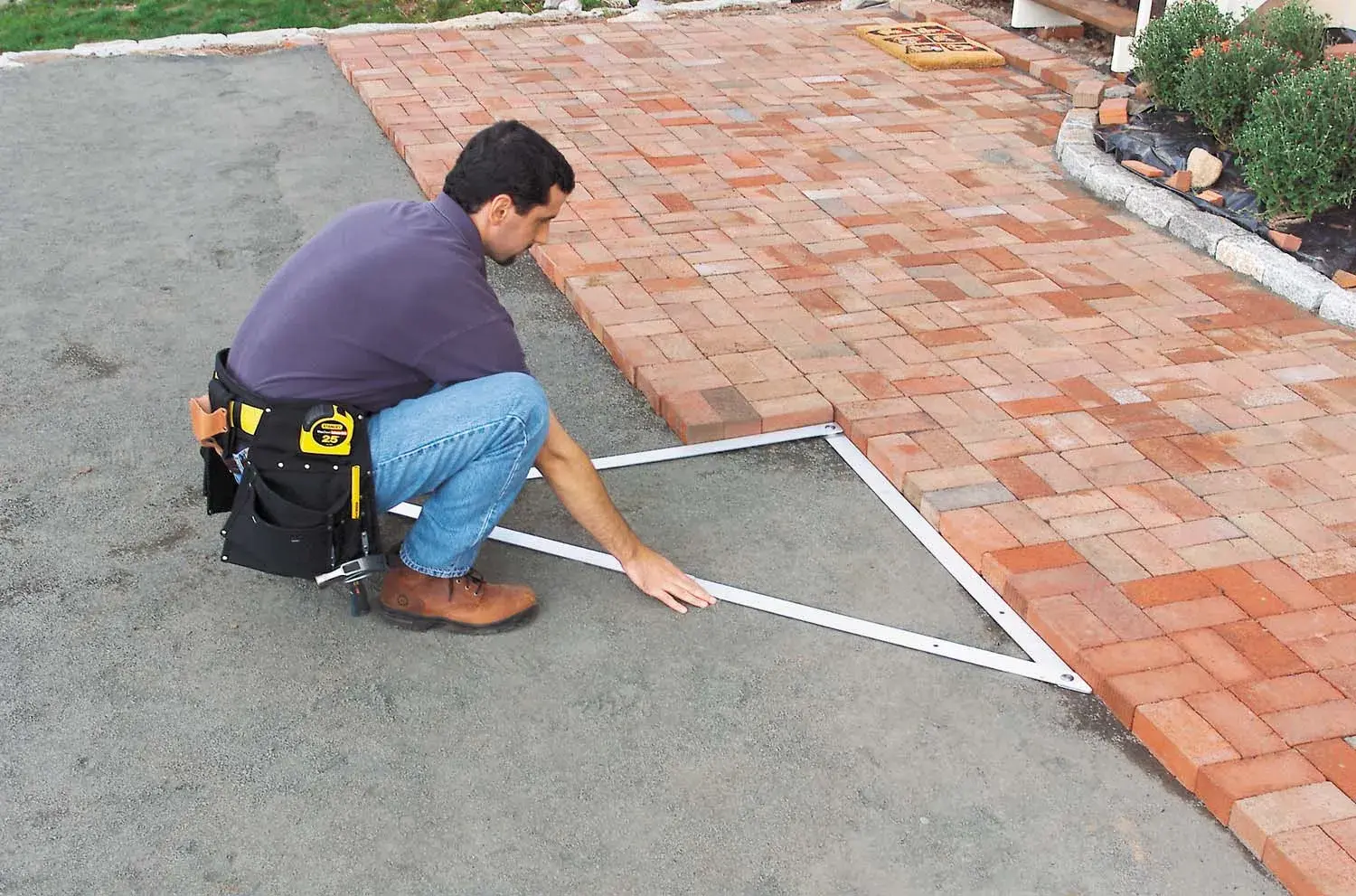 STANLEY 1-45-013 photography of a worker using a layout tool to align paving bricks on a patio.