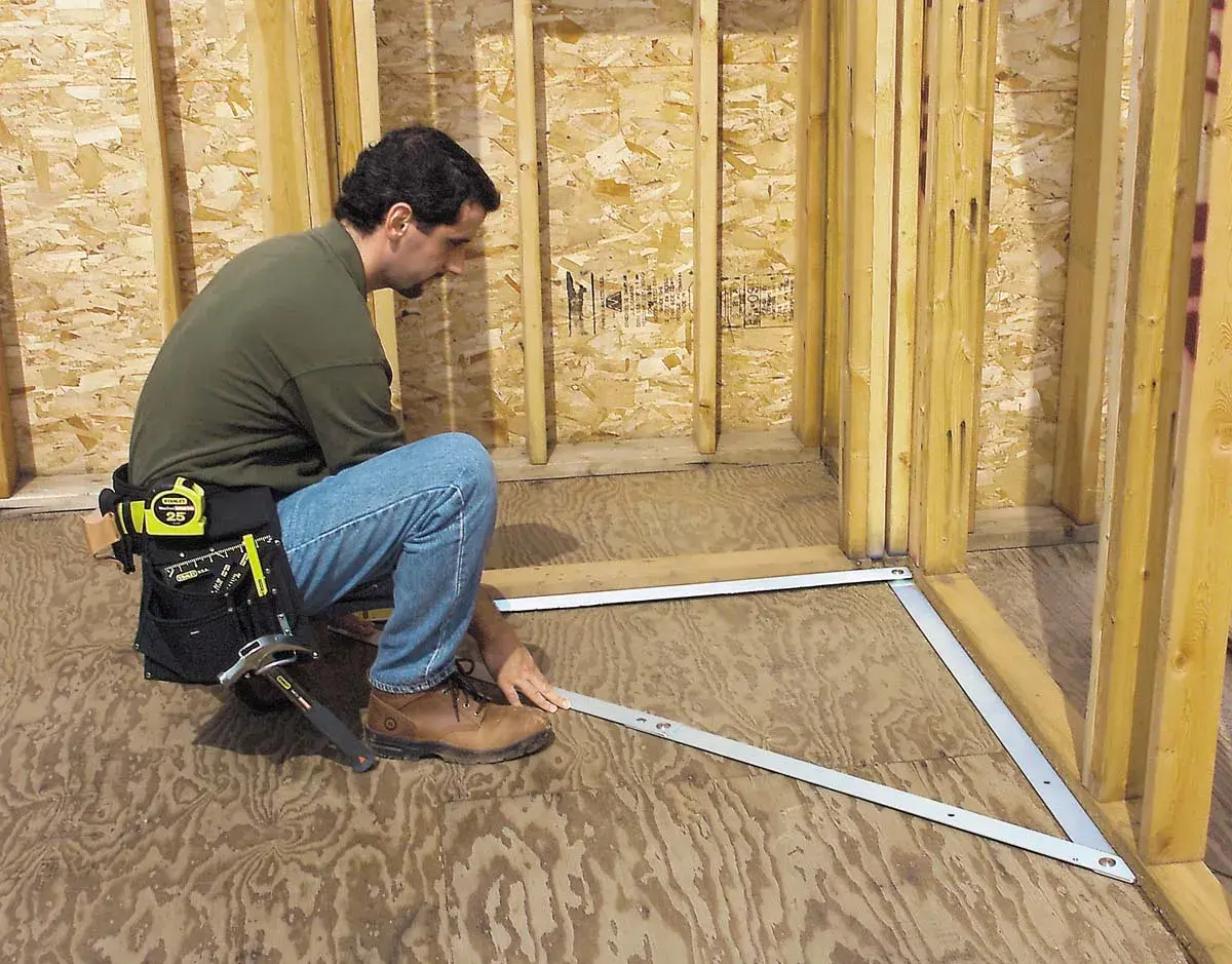 STANLEY 1-45-013 framing square tool in use on plywood floor during construction, product photography.