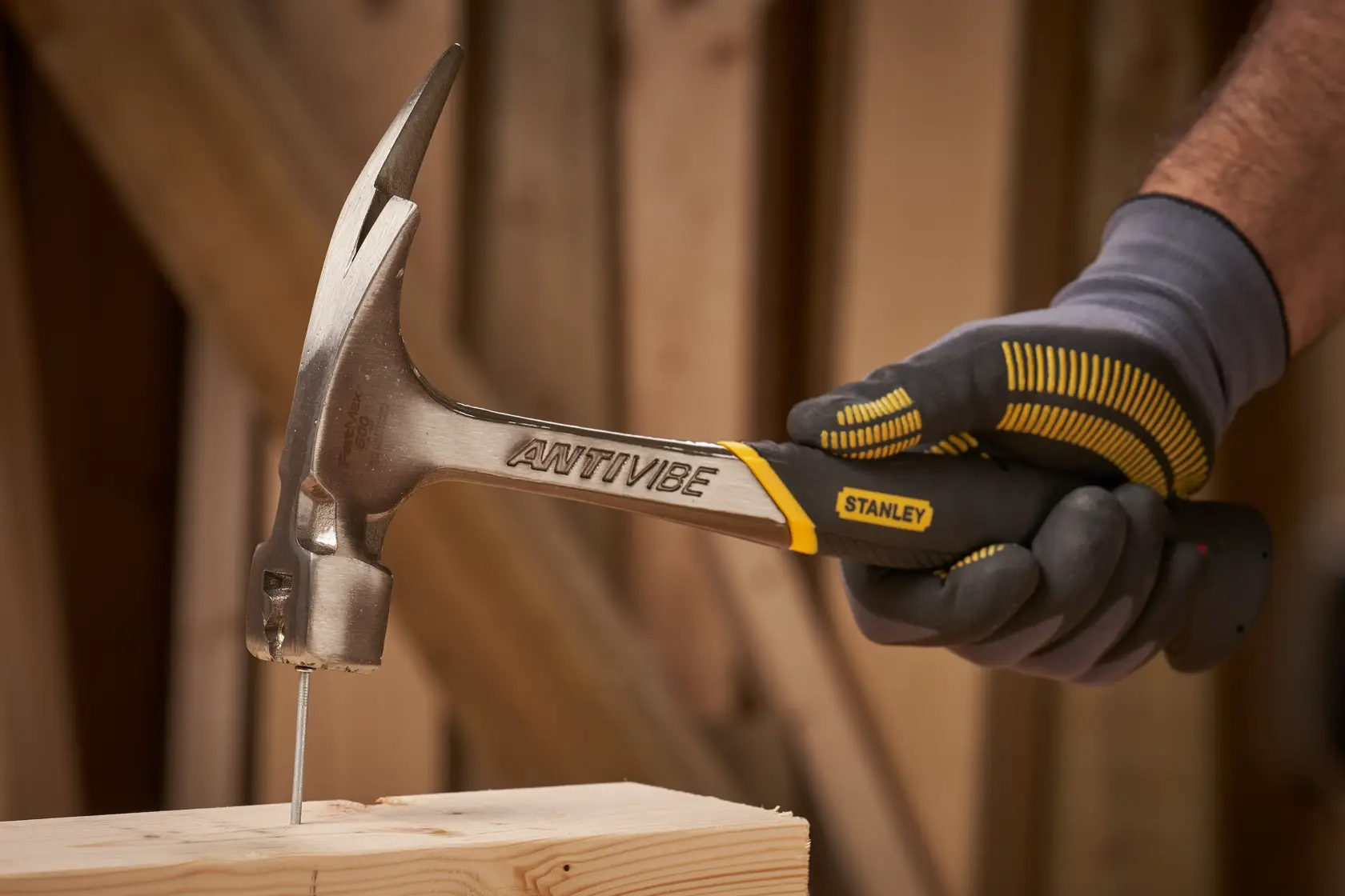 Stanley 1-51-937 claw hammer in use, driving a nail into wood, side angle photo.