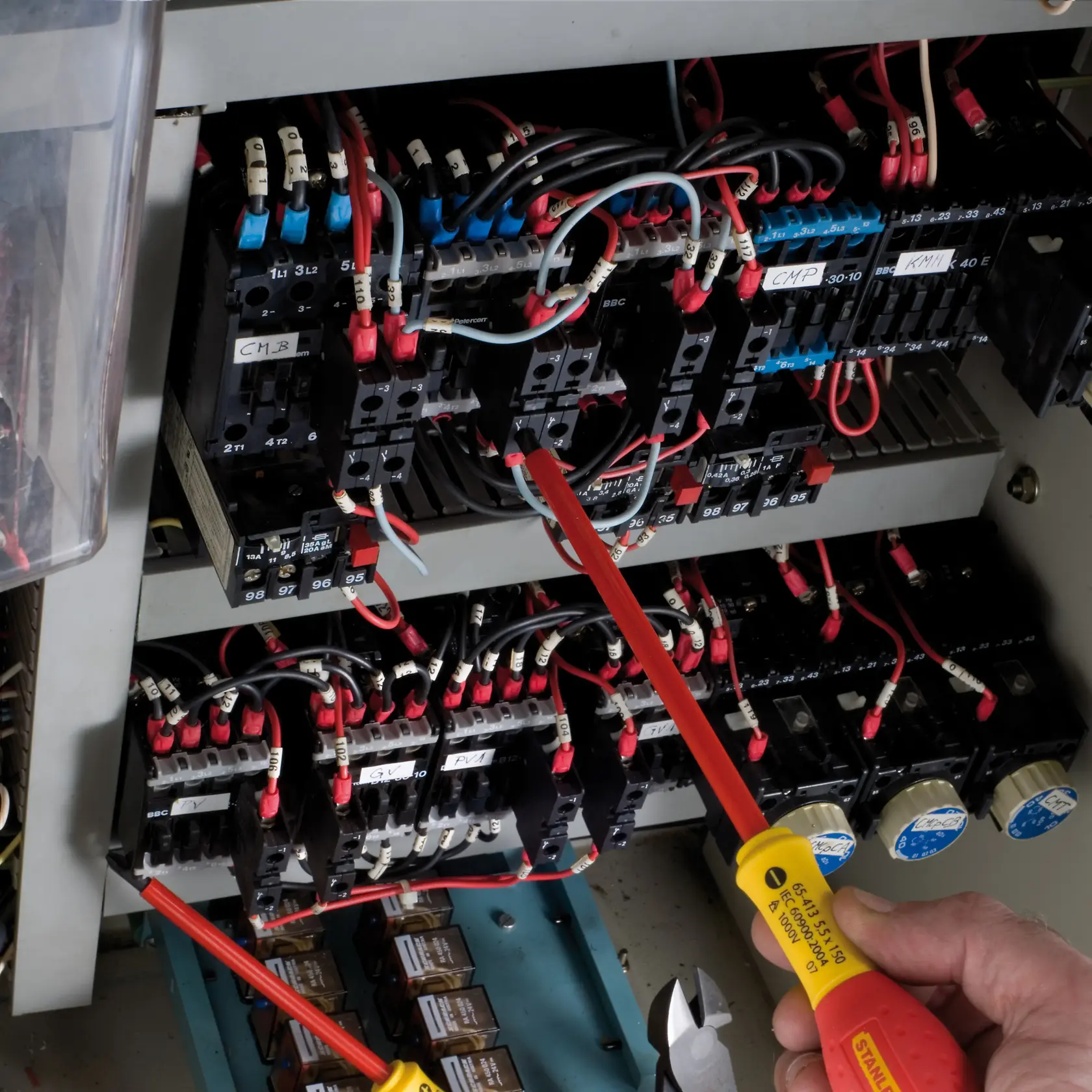 STANLEY 1-65-413 insulated screwdriver used on electrical panel with red and black wiring, side angle.