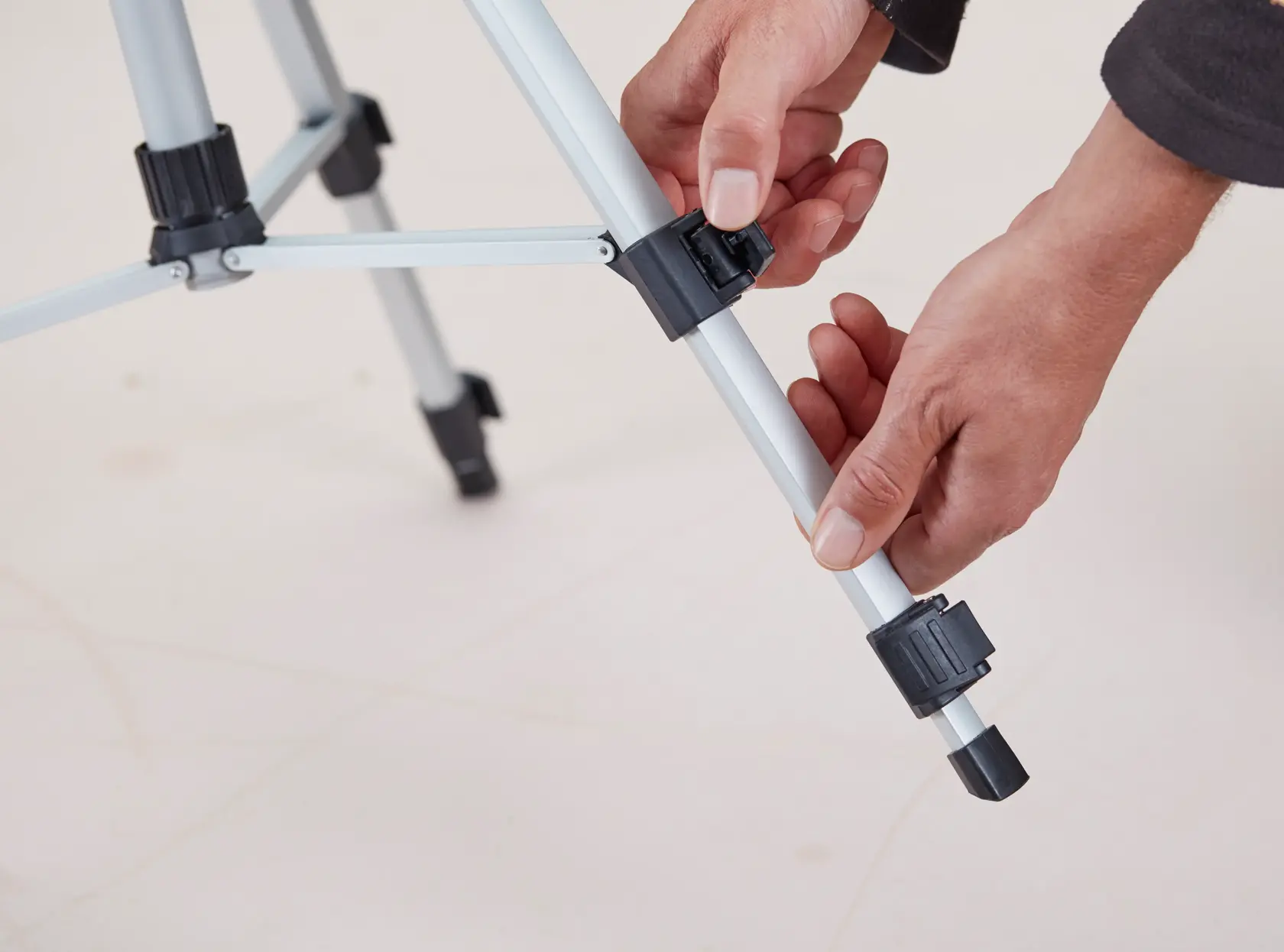 STANLEY 1-77-201 tripod photography, hands adjusting leg clamp on silver and black tripod.