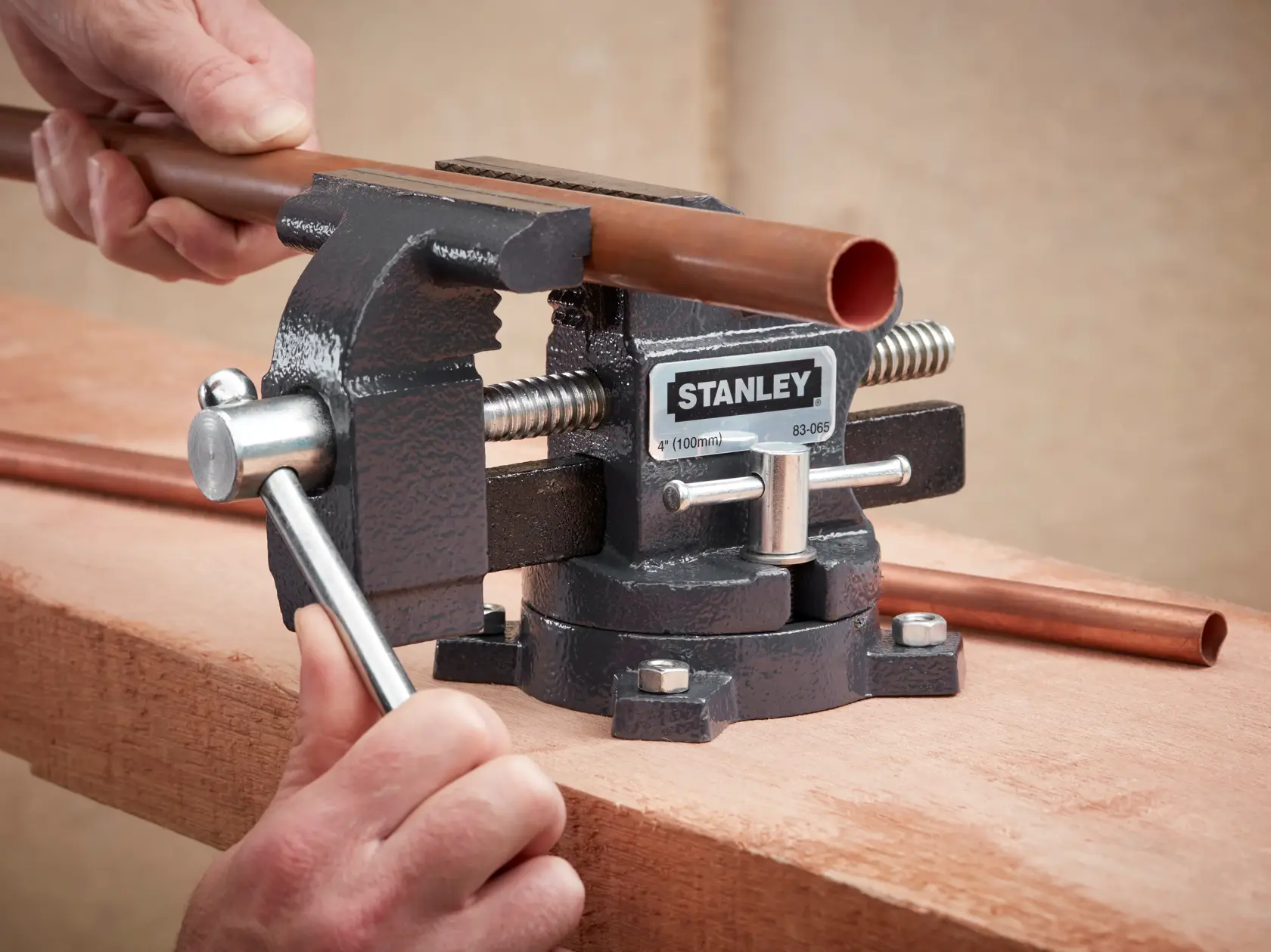 STANLEY 1-83-065 bench vice holding copper pipe on wooden surface, close-up photography.