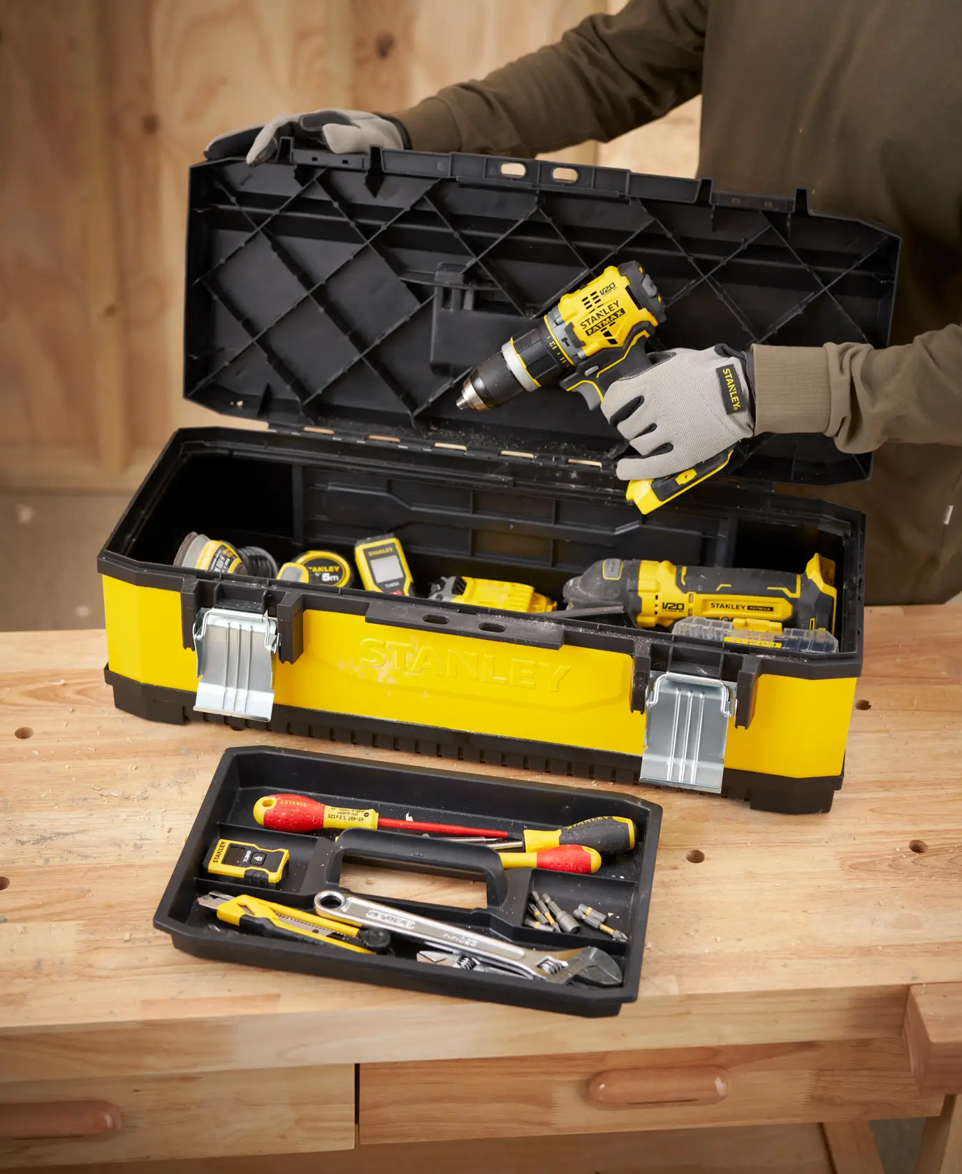 STANLEY 1-95-614 toolbox with yellow and black design, filled with assorted tools, shown on workbench, front angle