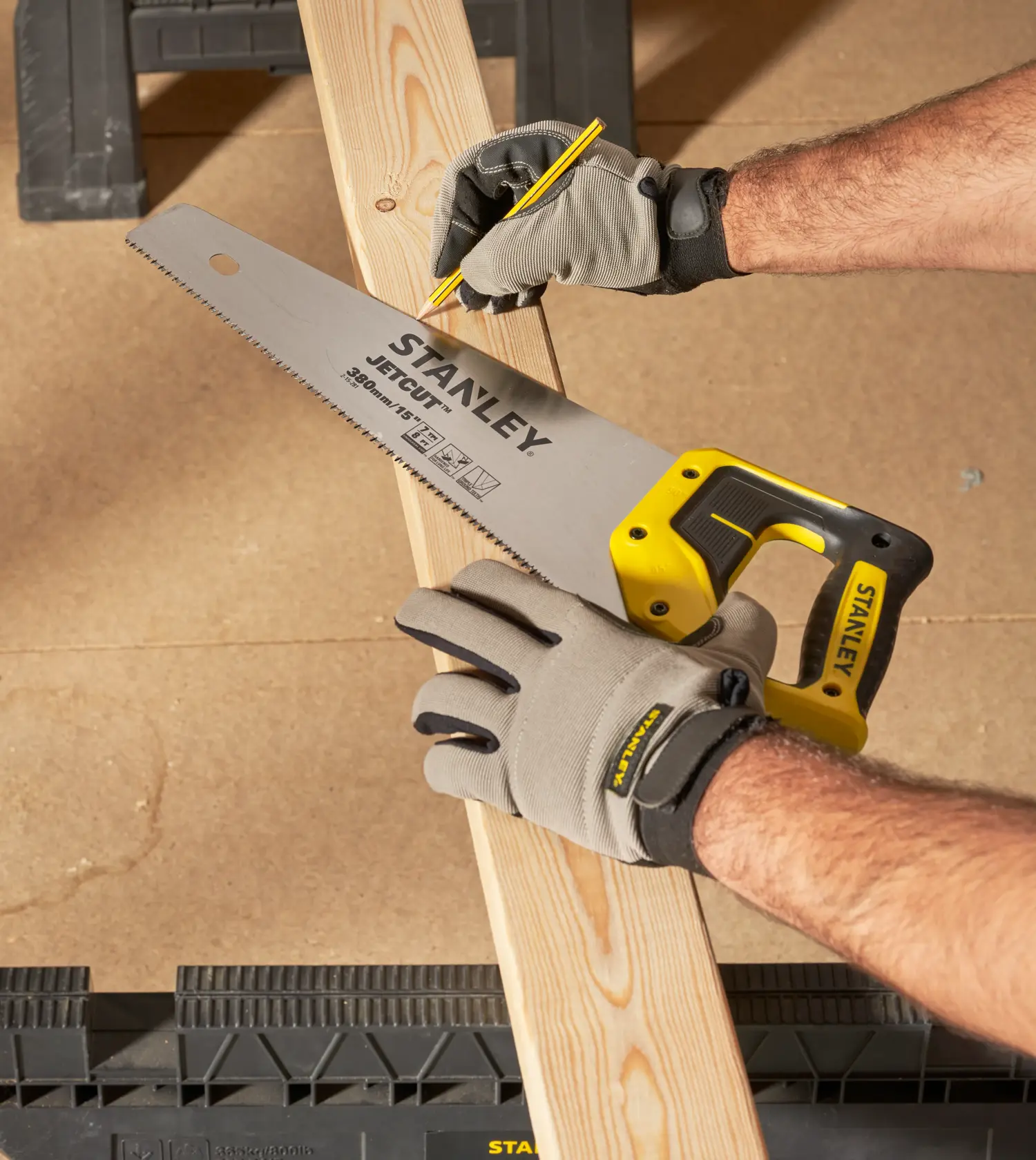 STANLEY 2-15-281 hand saw held on wooden plank, worker marking cut line, product photography.