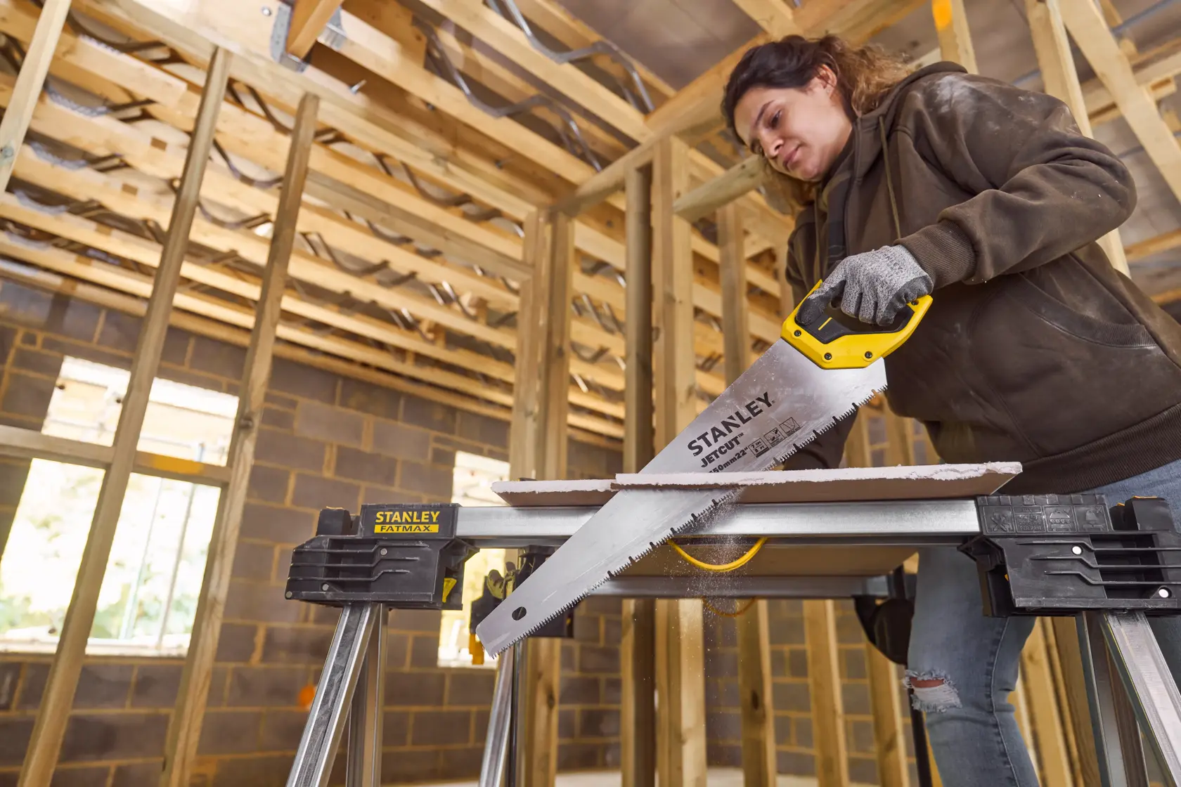 STANLEY 2-20-037 hand saw cutting wood, shown in action on STANLEY saw horses inside a framed construction site.