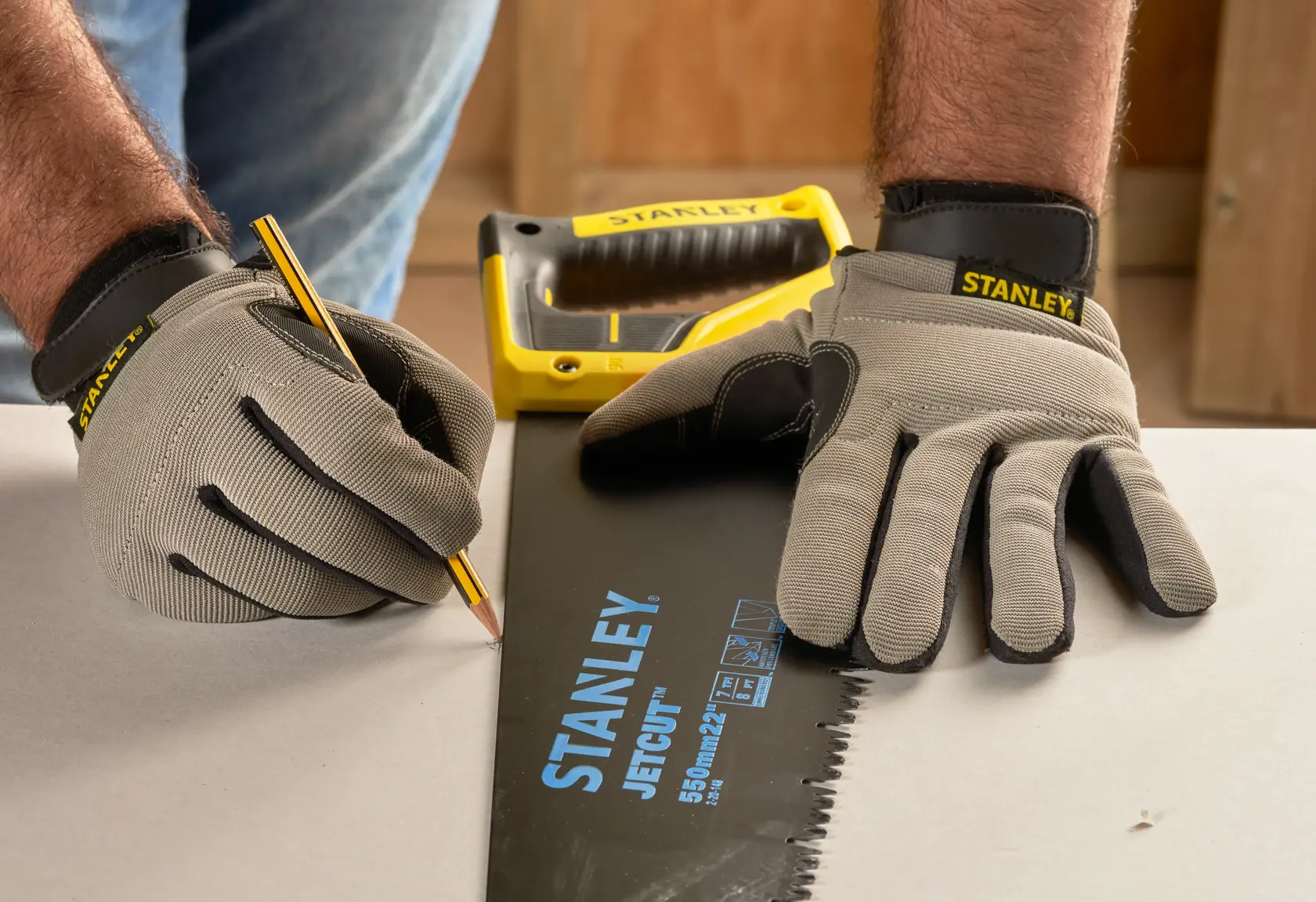 Photo of STANLEY 2-20-149 hand saw used for marking with gloves and pencil on a work surface.