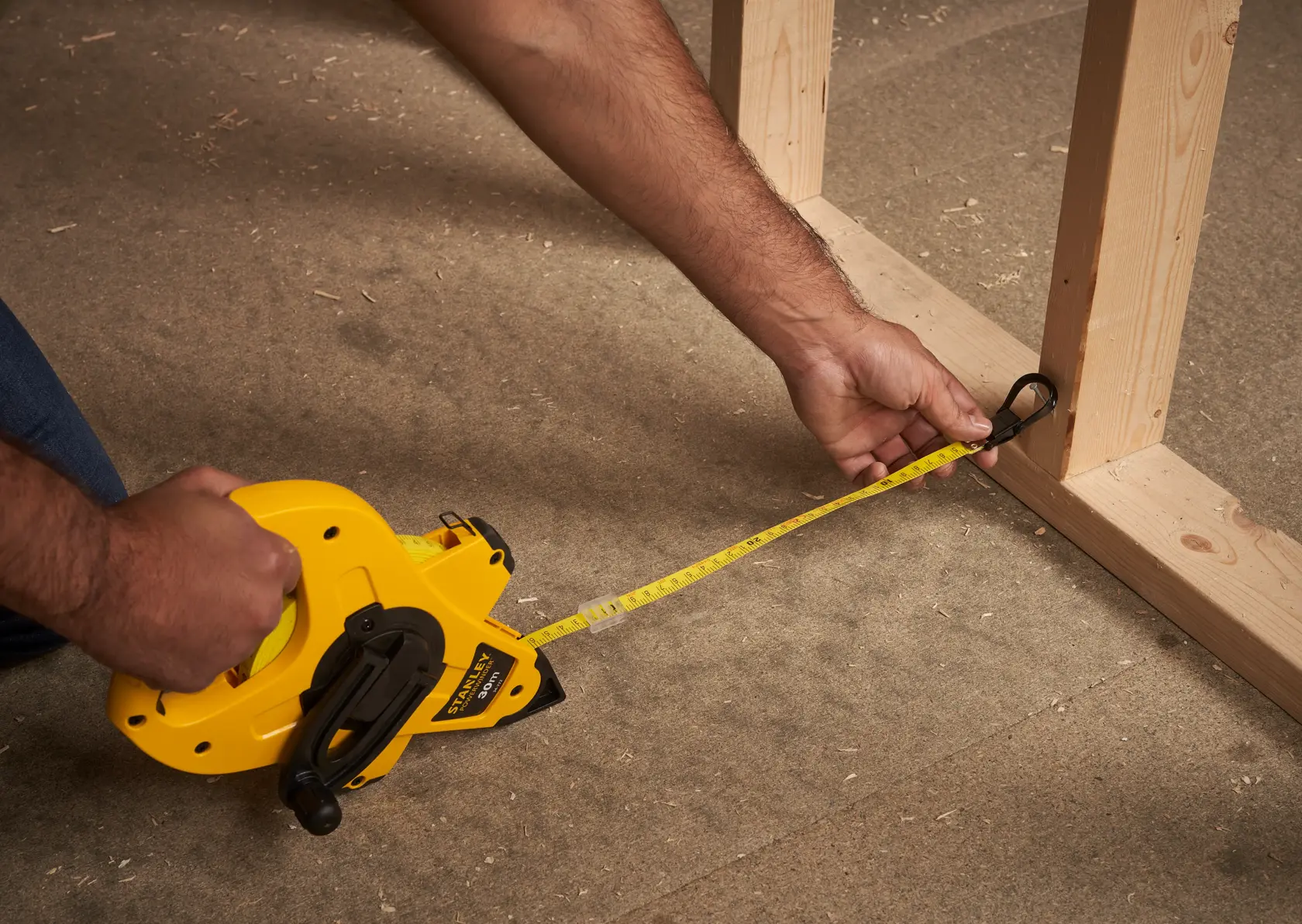 Photo of STANLEY 2-34-772 open reel tape measure being used to measure wood framing on a construction floor.