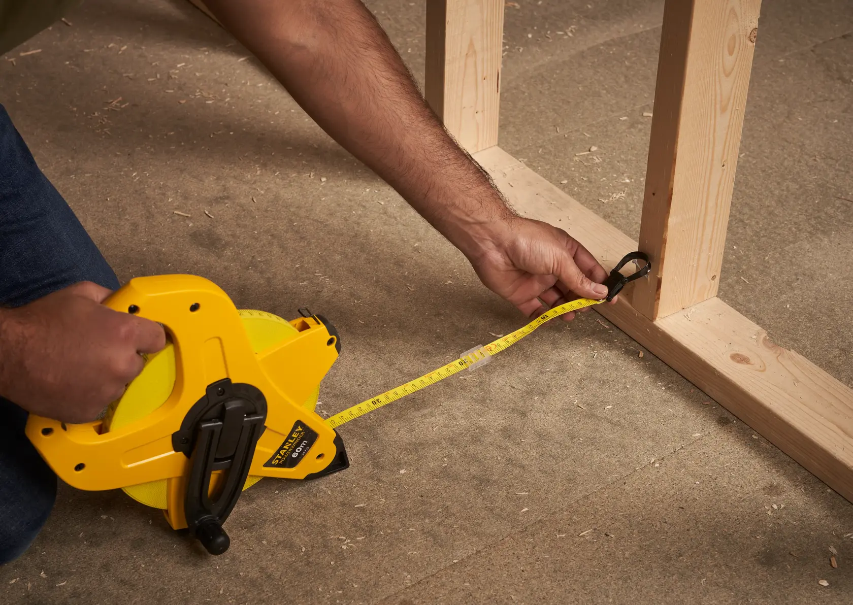 STANLEY 2-34-775 tape measure used to measure wood frame on floor, close-up of tape extended.