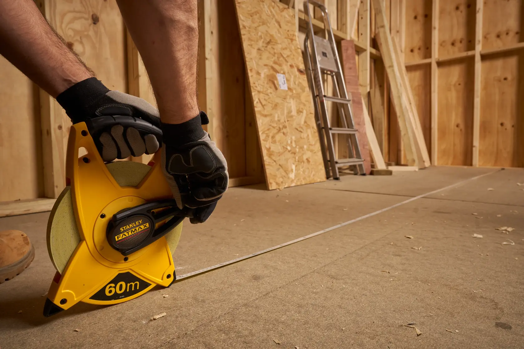 Photo of STANLEY 2-34-824 open reel measuring tape, 60m, used on construction site floor.