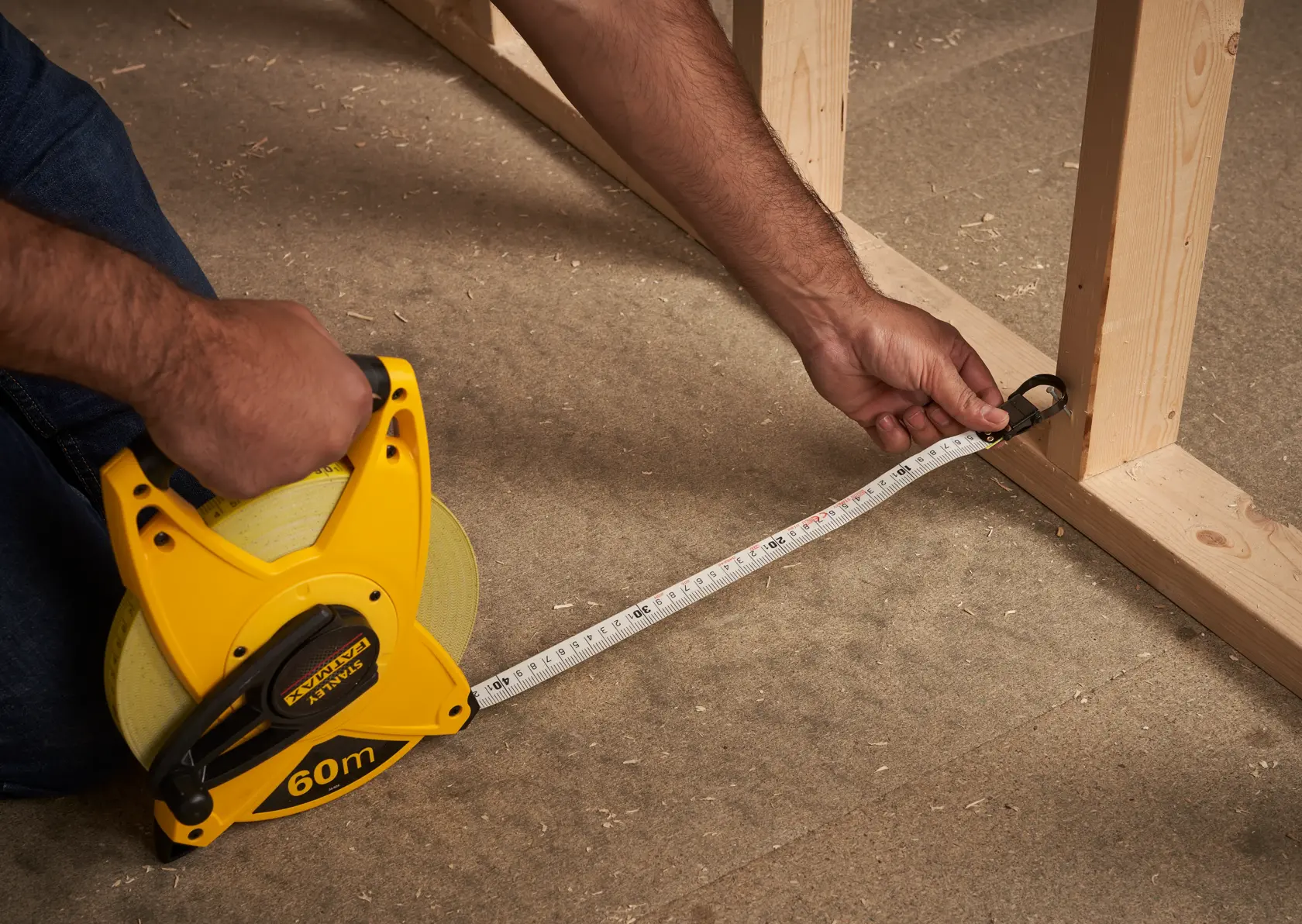 STANLEY 2-34-824 measuring tape reel, 60m, photography of product in use measuring wooden frame.