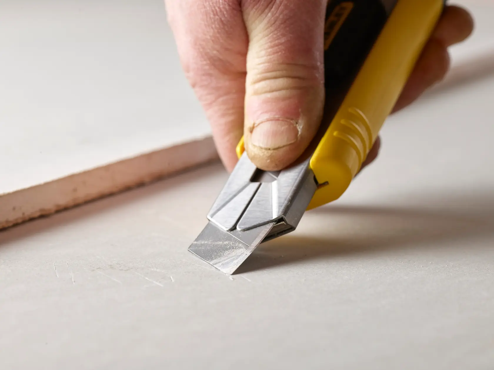 STANLEY 3-11-725 utility knife with yellow handle used to cut drywall, close-up photography.