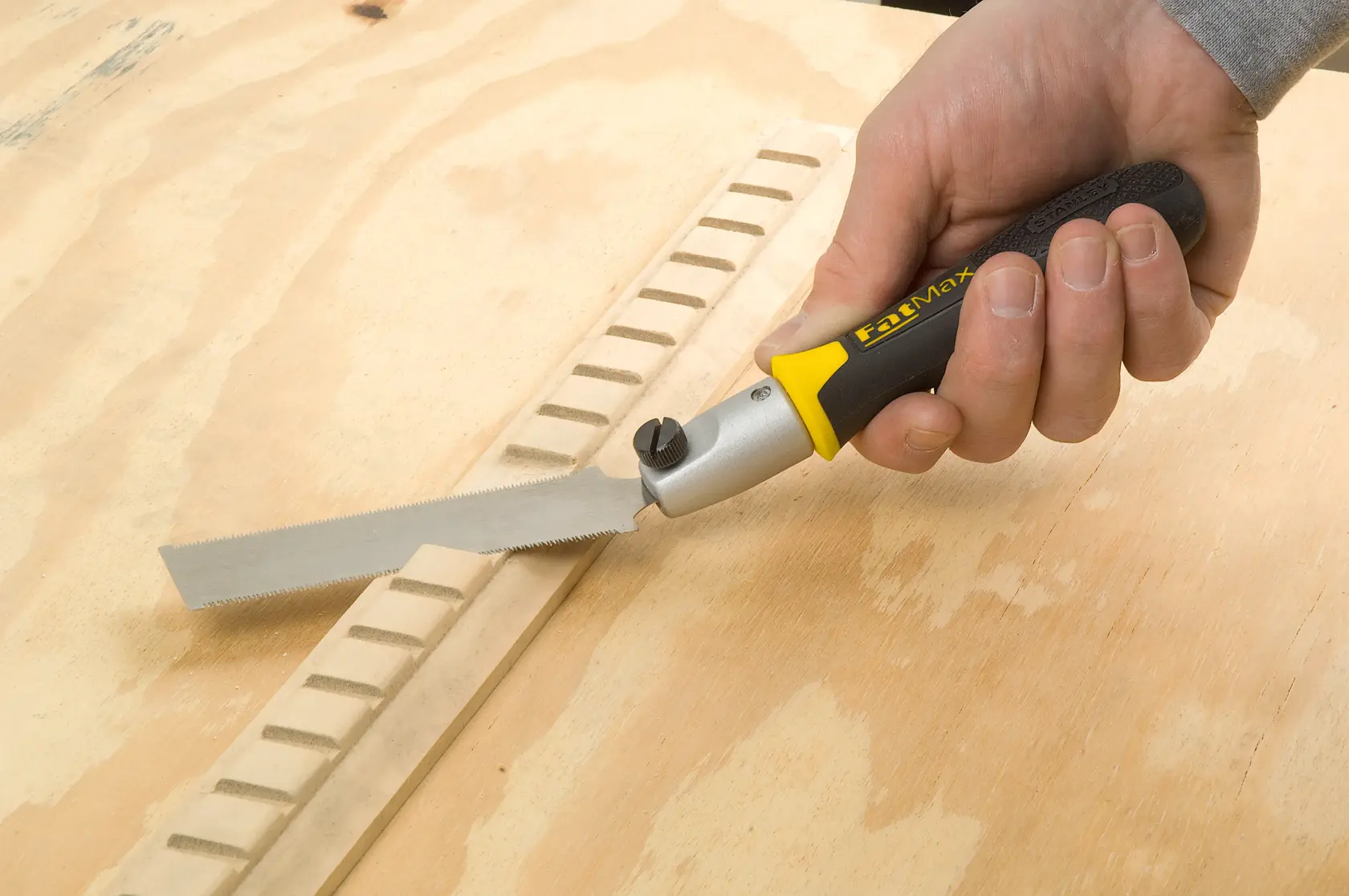 STANLEY 3-20-331 folding saw with black and yellow handle used on wood surface, close-up photo.