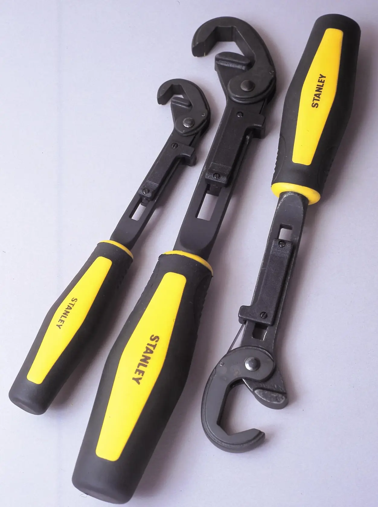 STANLEY 4-87-988 set of three adjustable wrenches with black metal jaws and yellow-black handles, angled view.