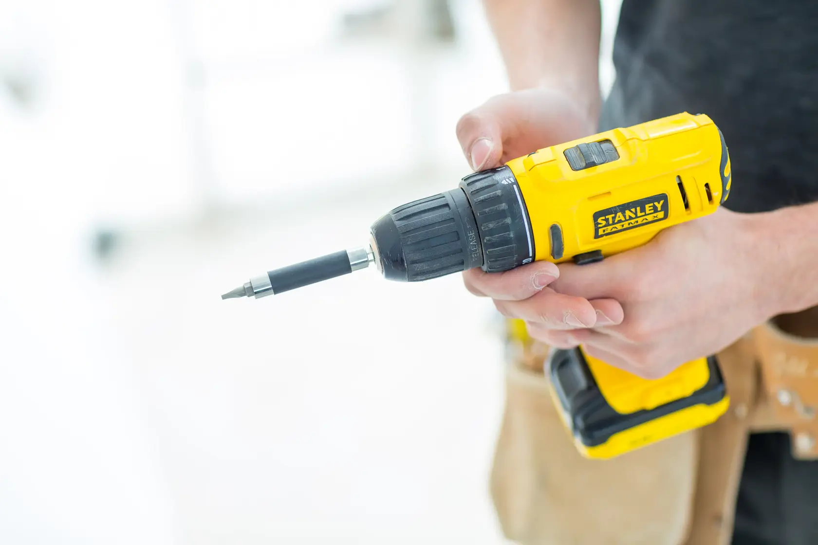Photo of STANLEY FMC011S2 cordless drill held in hand, yellow and black, side angle.