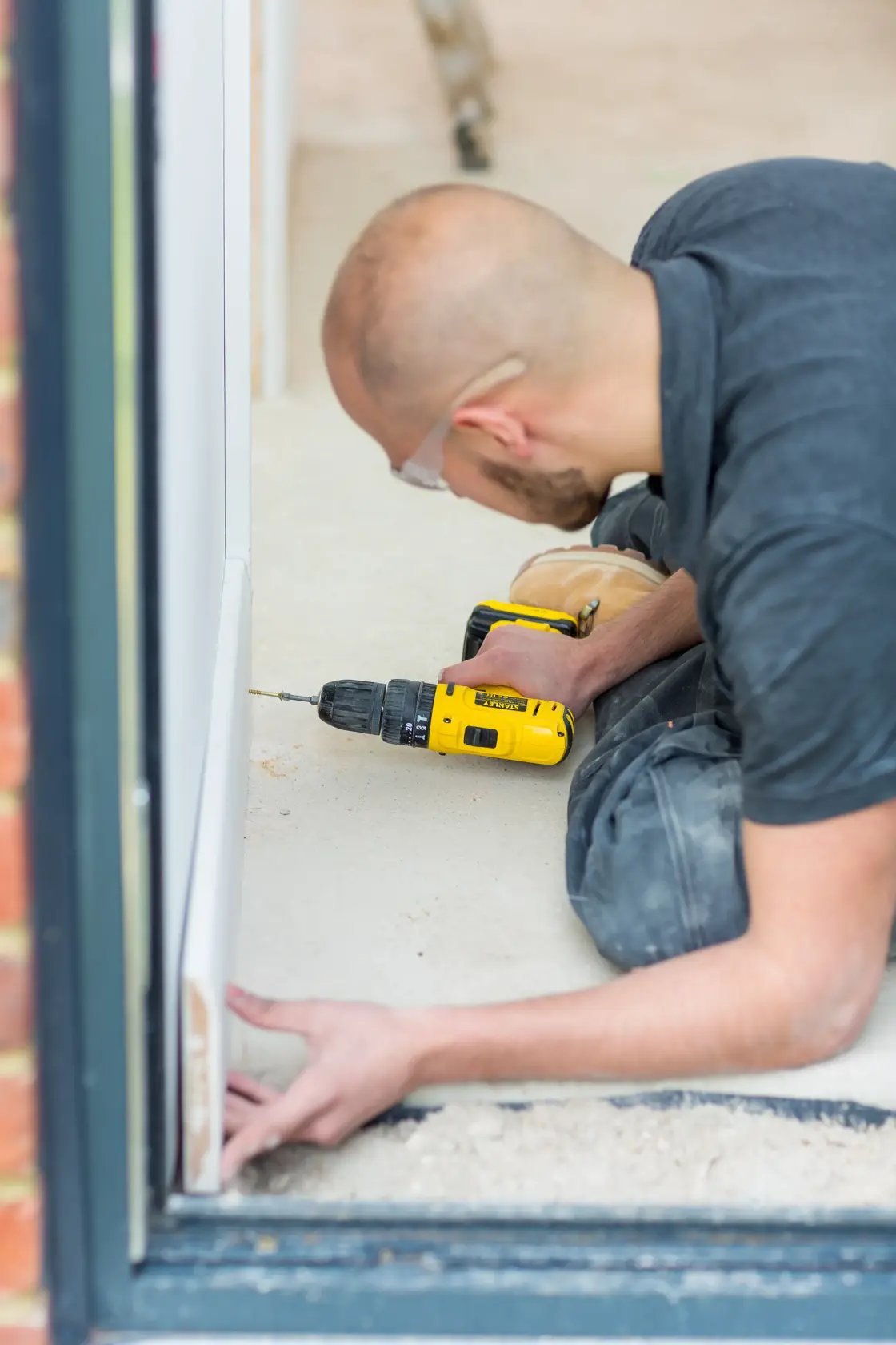 STANLEY FMC021S2 cordless drill used by person assembling white frame on floor, photography side angle.