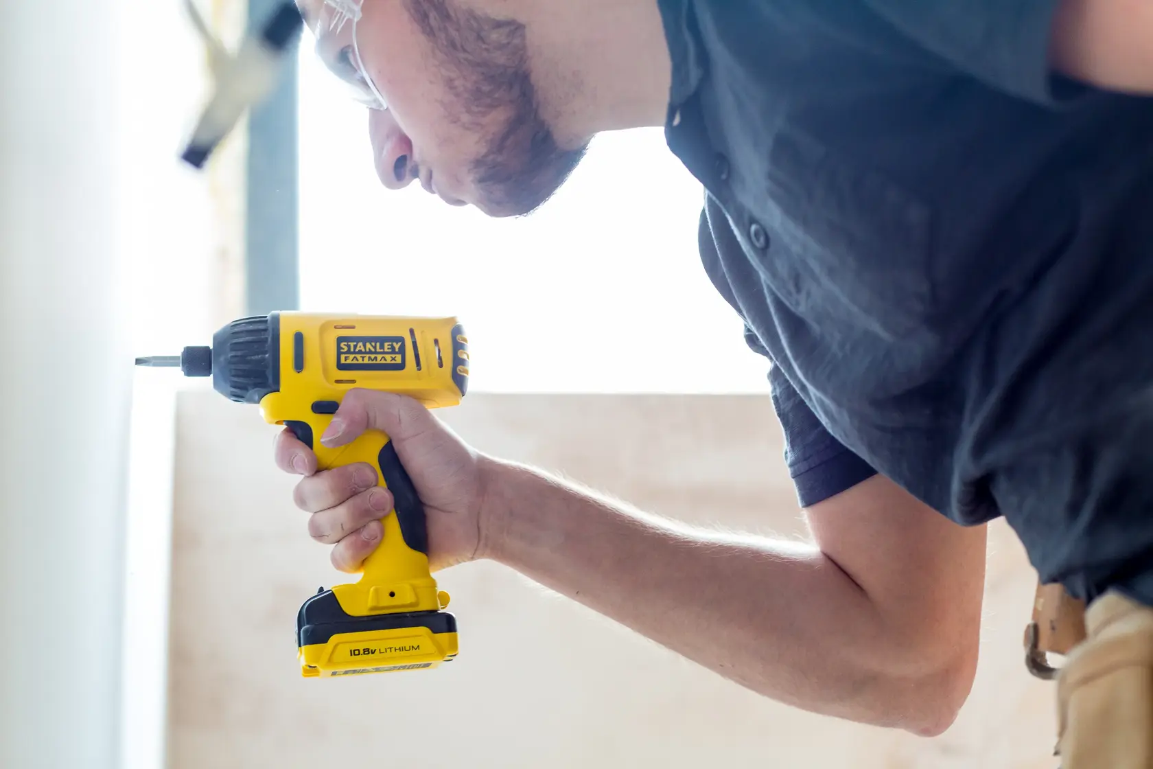 Photo of STANLEY FMC041S2 cordless drill in use, yellow and black design, held by a person.