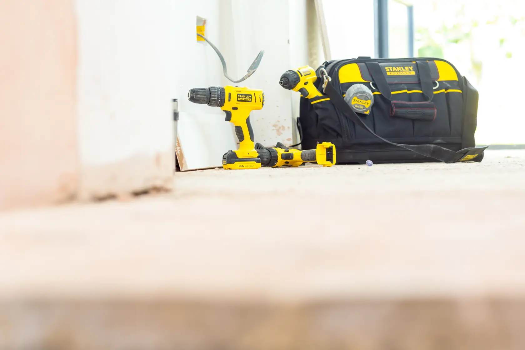 STANLEY FMC041S2 cordless drill set with yellow tools and black tool bag on floor, side angle.