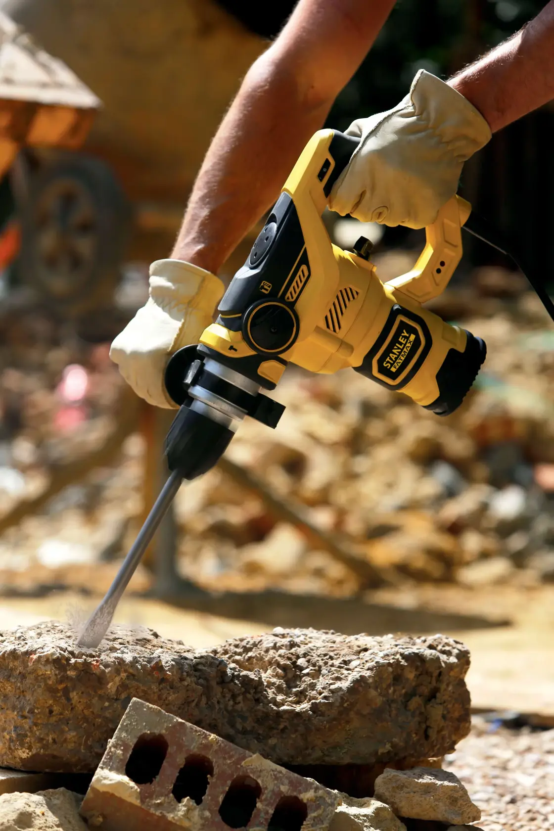 STANLEY FME1250K rotary hammer in use, yellow and black design, drilling into concrete at construction site.