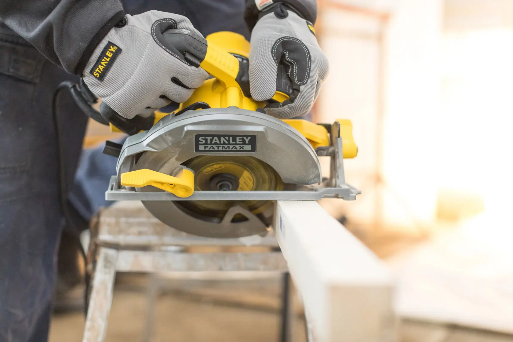 STANLEY FME301 circular saw cutting wood, close-up, with operator wearing gloves, photography.