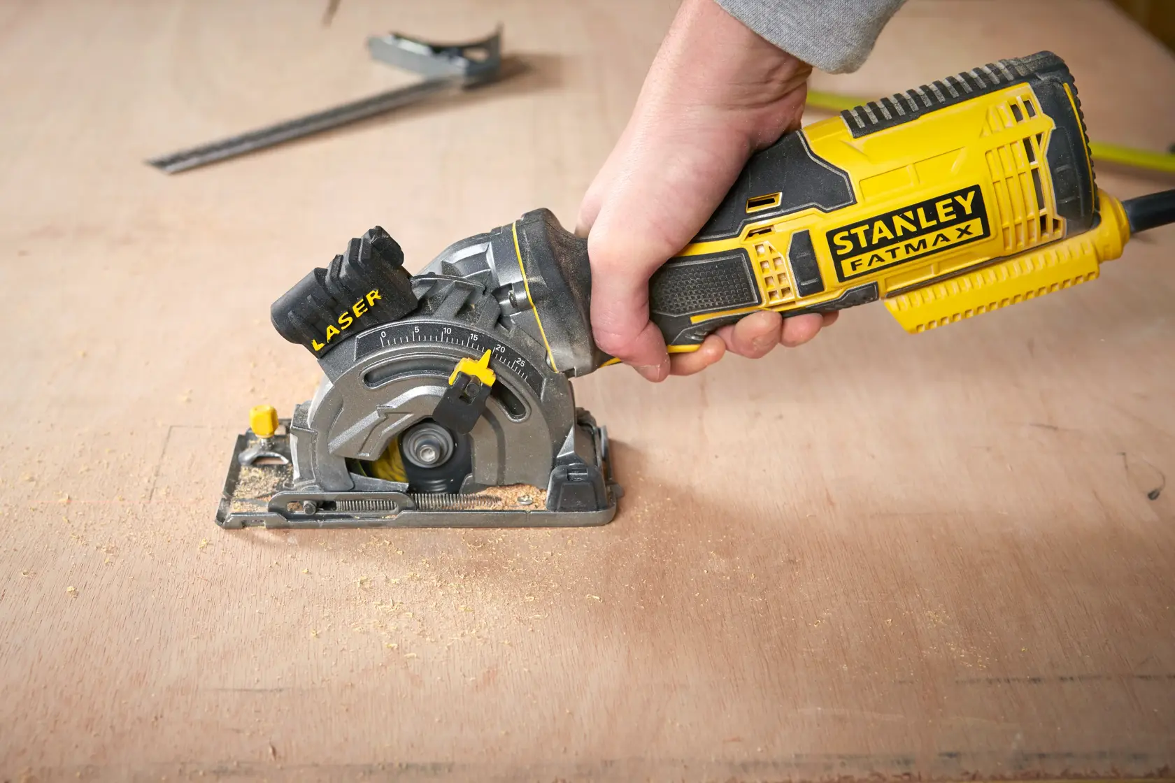 Photo of STANLEY FME380K handheld circular saw with laser cutting guide in use on wood surface.