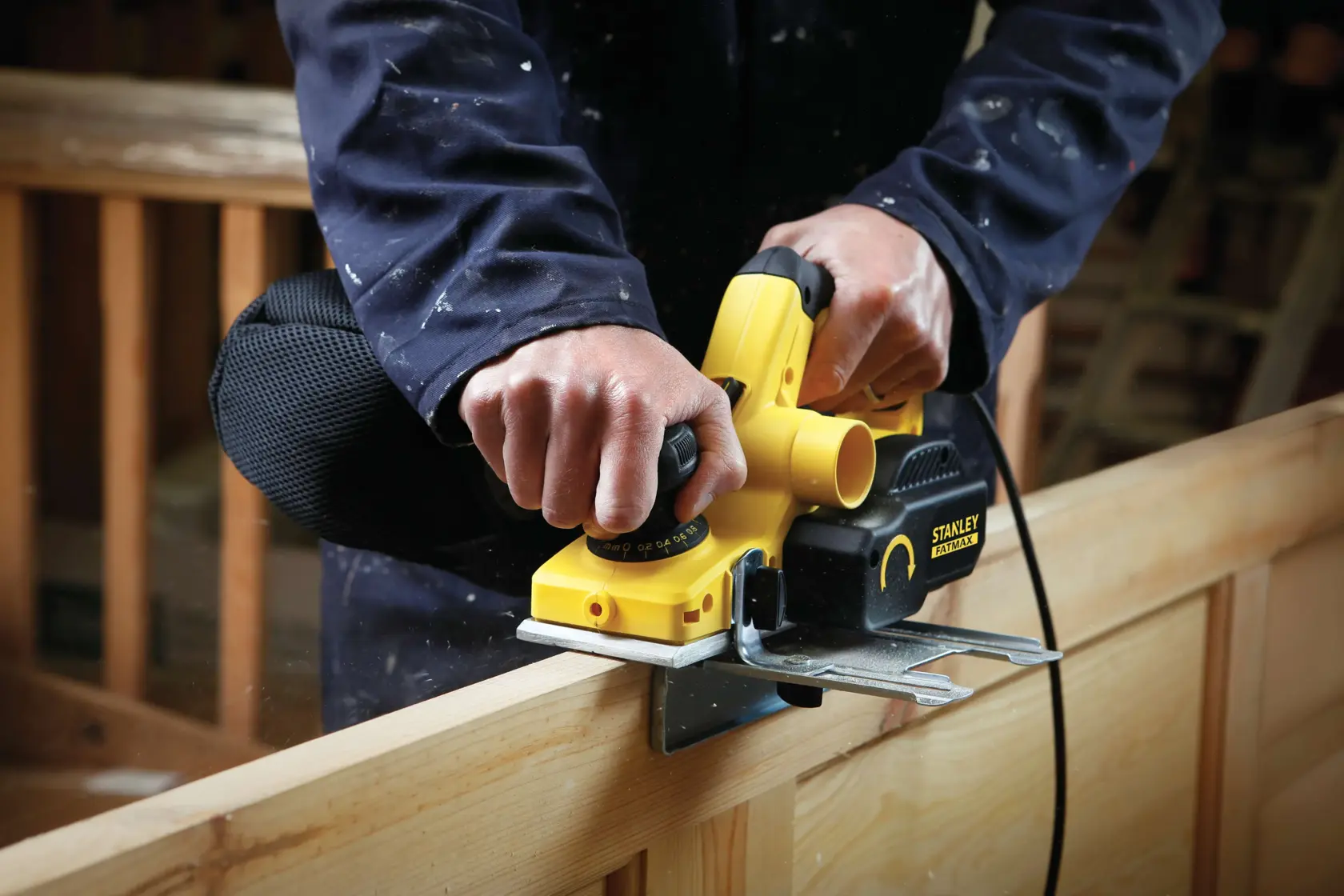 Photo of STANLEY FME630 planer smoothing wood, close-up of tool in use by person in workshop.