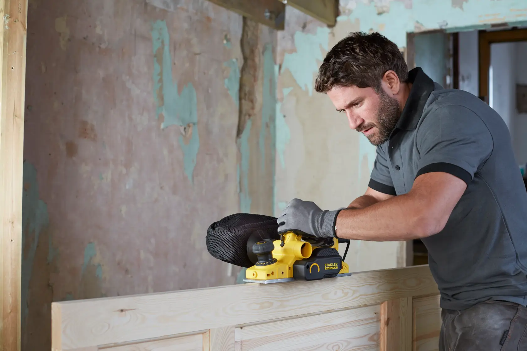 Photo of STANLEY FME630 belt sander in use on wood surface during renovation, side view.