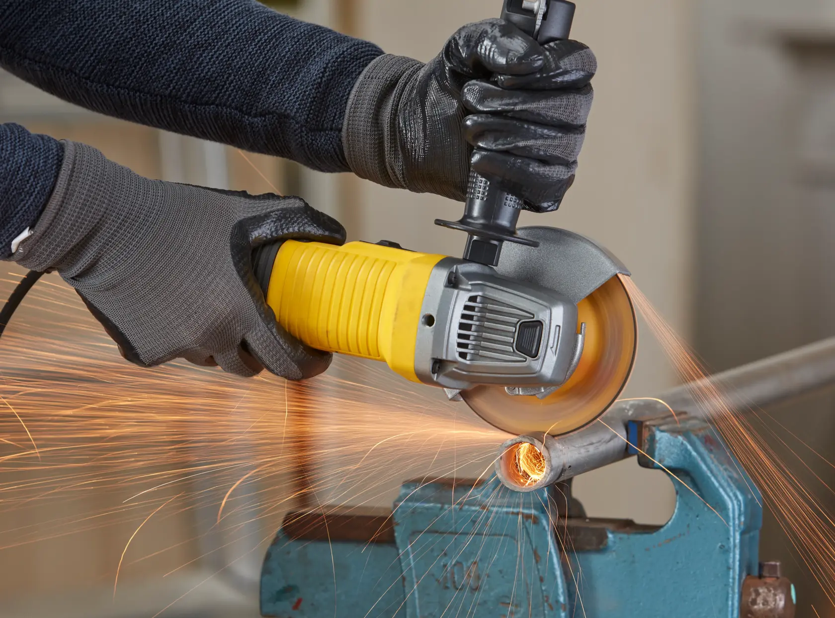 STANLEY FMEG210K angle grinder in use, cutting metal pipe with sparks, close-up photography.