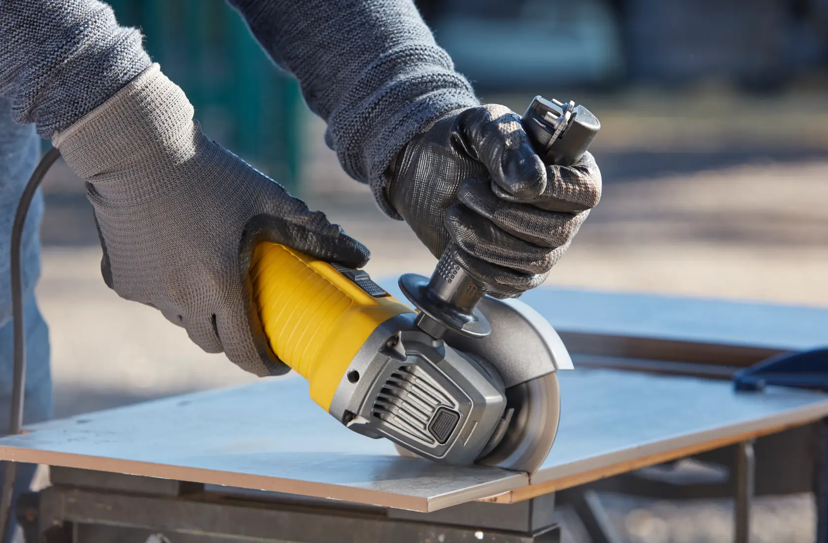 STANLEY FMEG210K angle grinder in use, yellow and black, cutting tile on workbench.