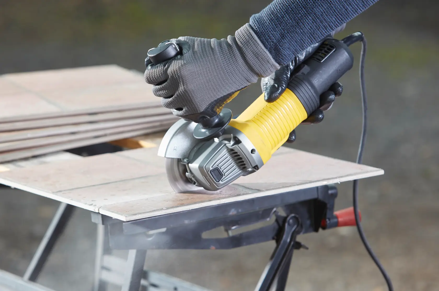 STANLEY FMEG210 angle grinder cutting tiles, close-up photo of tool in use, photography product category.