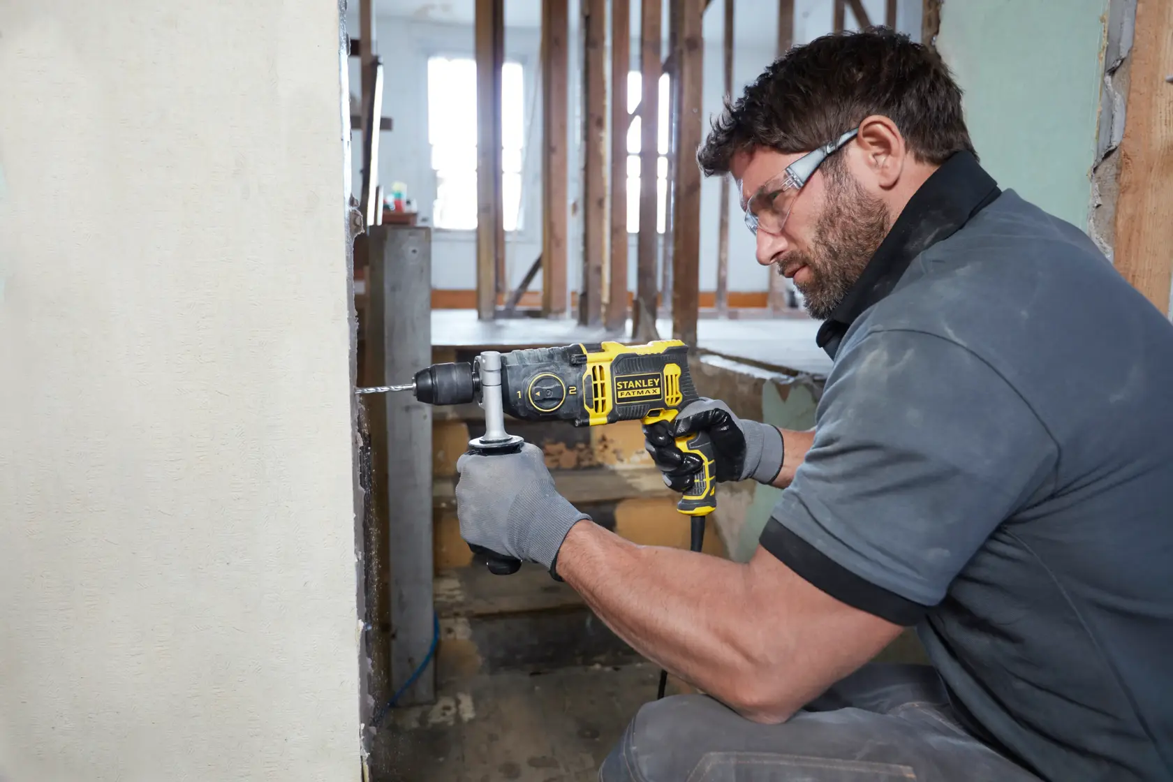STANLEY FMEH850K hammer drill in use, drilling into a wall, construction site setting.