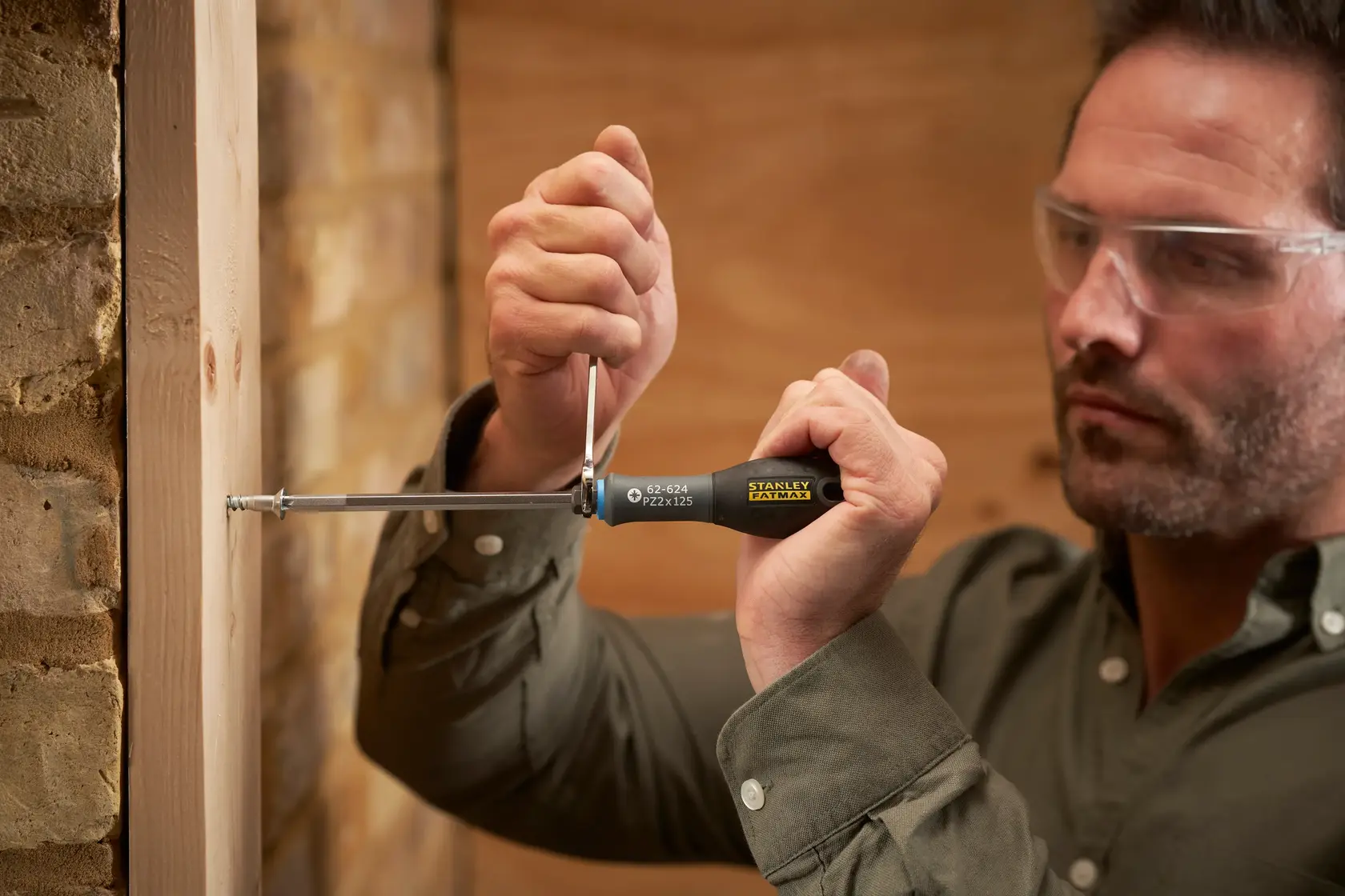 Photo of man using STANLEY FMHT0-62624 screwdriver to drive screw into wood frame indoors.
