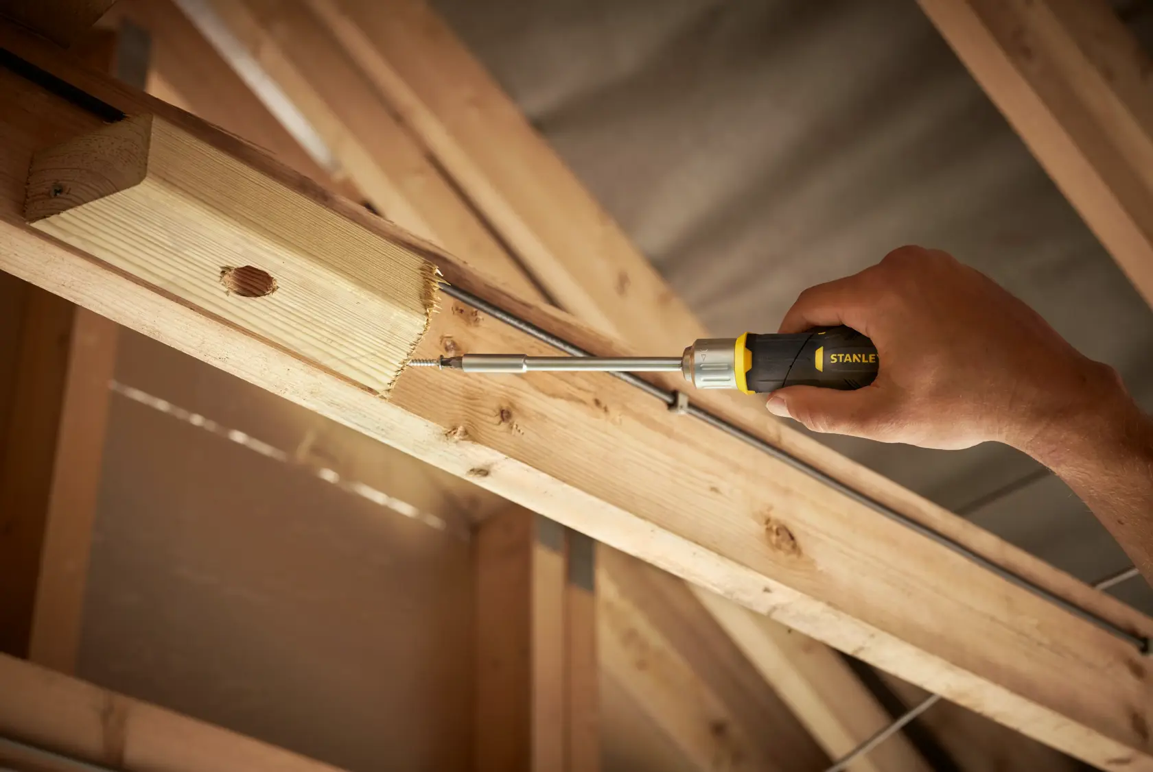 STANLEY FMHT0-62691 screwdriver used on wood beam, side angle, photo of product in construction setting.