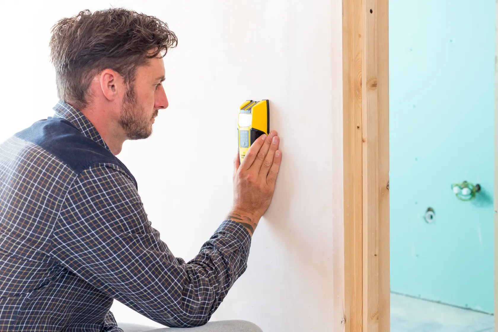Photo of a person using a STANLEY FMHT0-77407 wall scanner tool against a white wall, product in hand.