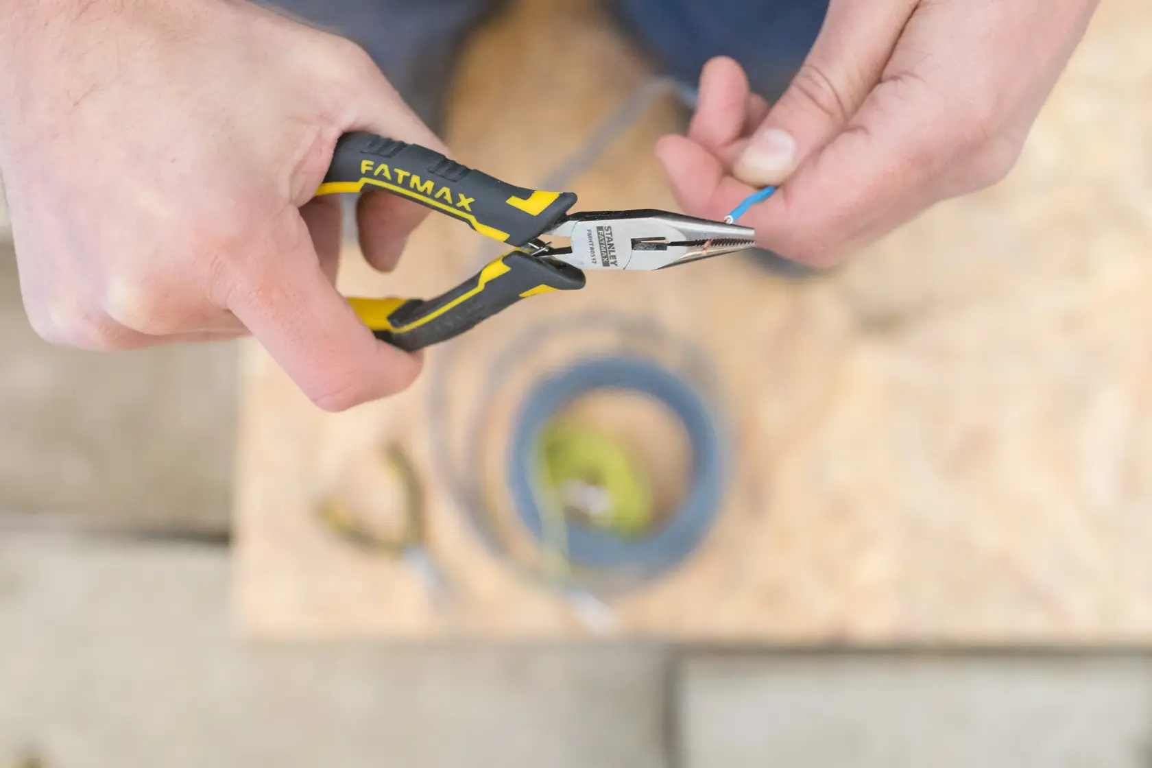 STANLEY FMHT0-80517 long nose pliers with yellow-black handle in use, gripping blue wire.